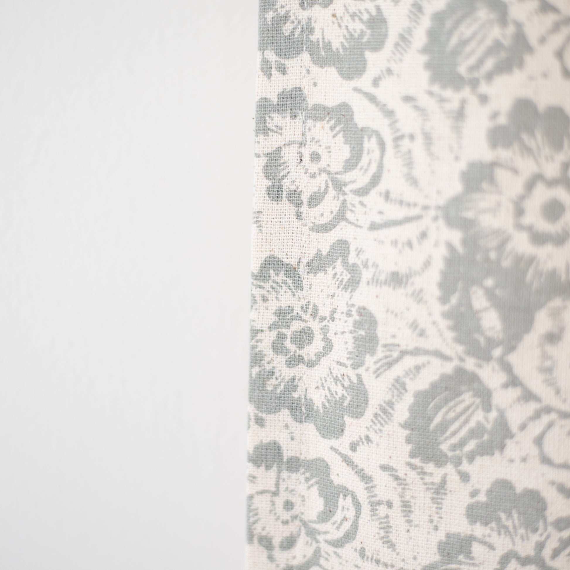 Cream curtain panel with gray floral and damask pattern in woven fabric texture.