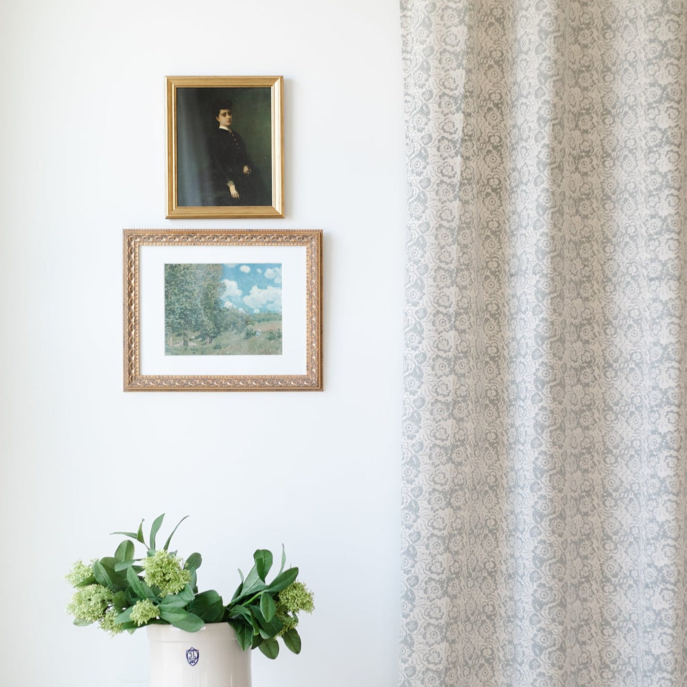 Pair of beige curtain panels with repeating floral damask pattern, displayed hanging at window.