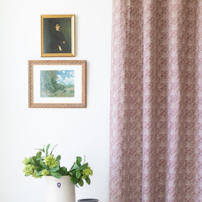 Two mauve curtain panels with damask pattern hanging at window.