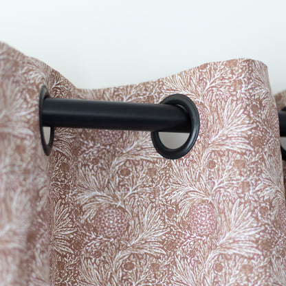 Two taupe curtain panels with white floral damask pattern hung on black grommet rod.
