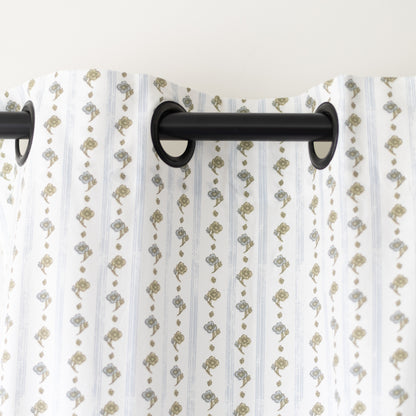 Two white curtain panels with tan and gray botanical print pattern hung on black rod.