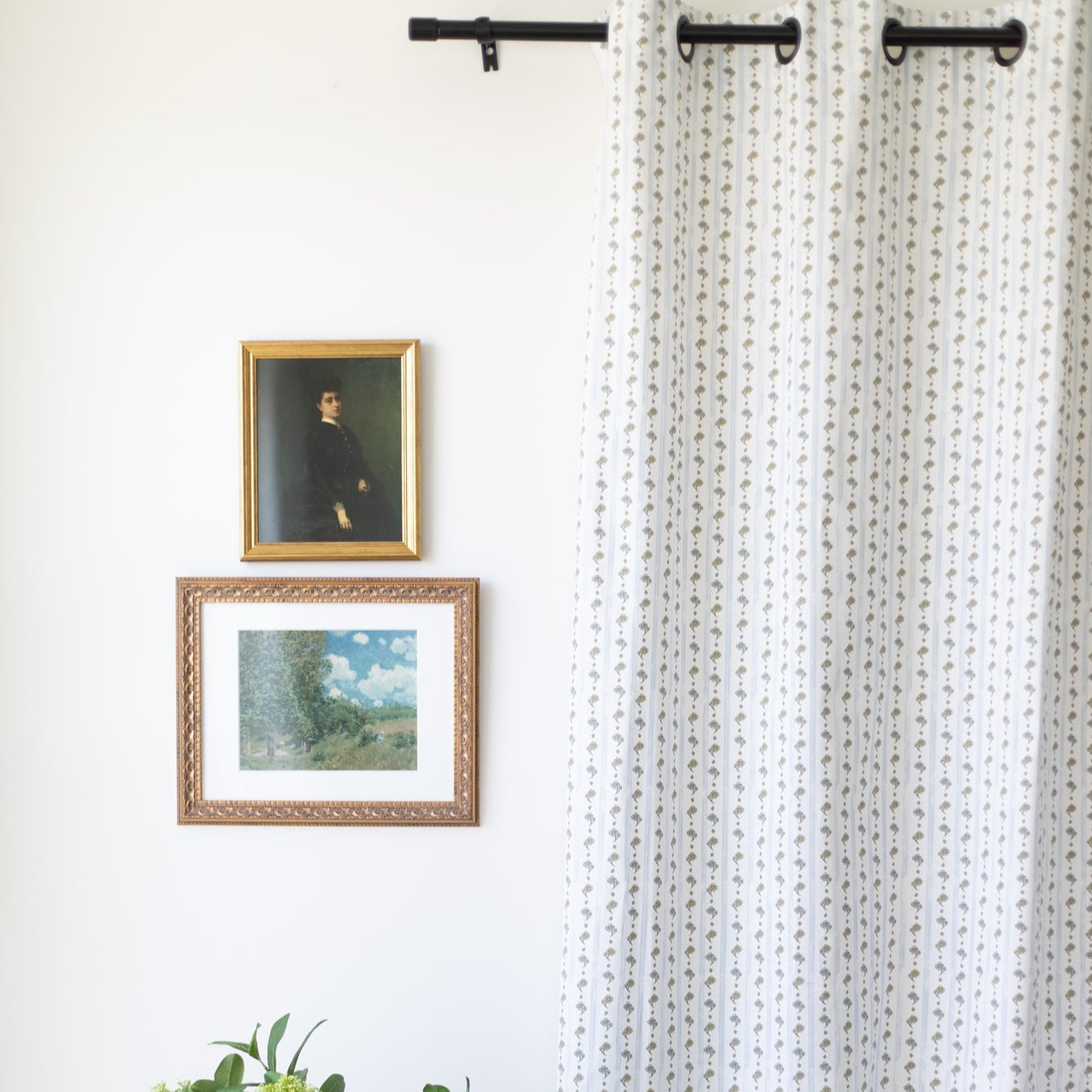 Two cream curtain panels with small floral print hung on black rods, displayed in window setting.