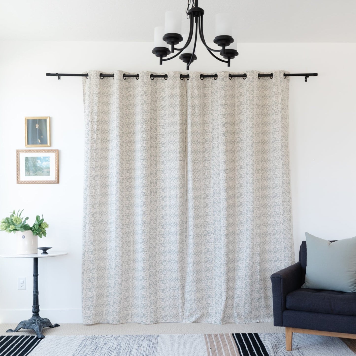 Two beige curtain panels with geometric pattern hanging from black rod with grommet top.