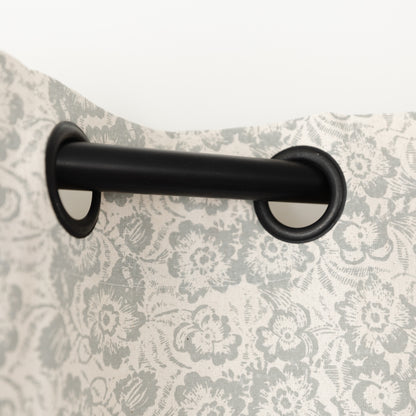 Two cream curtain panels with gray floral pattern hung on black grommet rod.