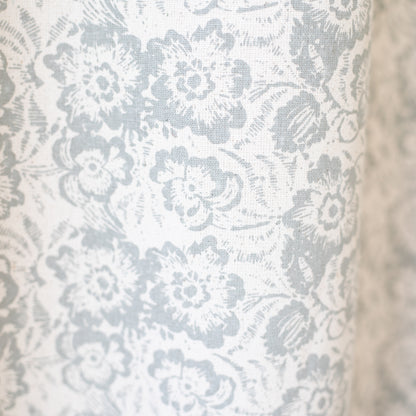 White and gray floral patterned curtain panel with textured fabric weave.