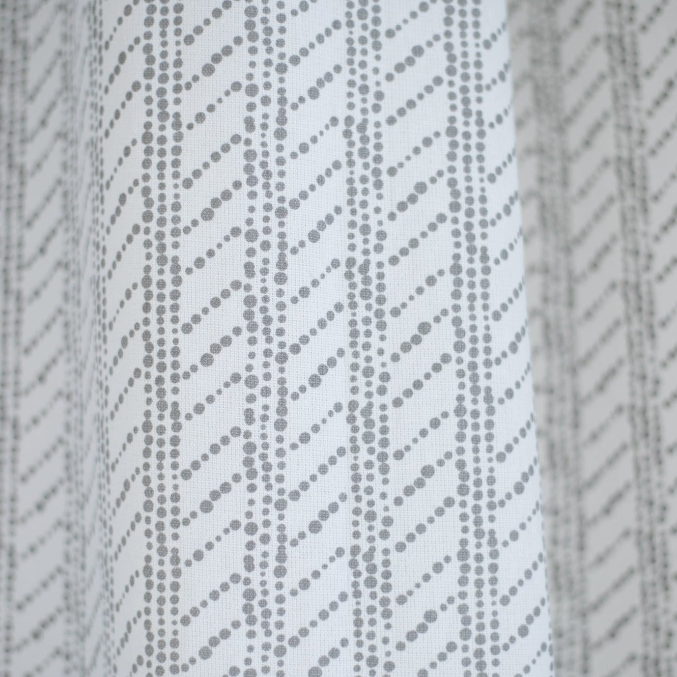 White shower curtain with gray diagonal dotted stripe pattern.
