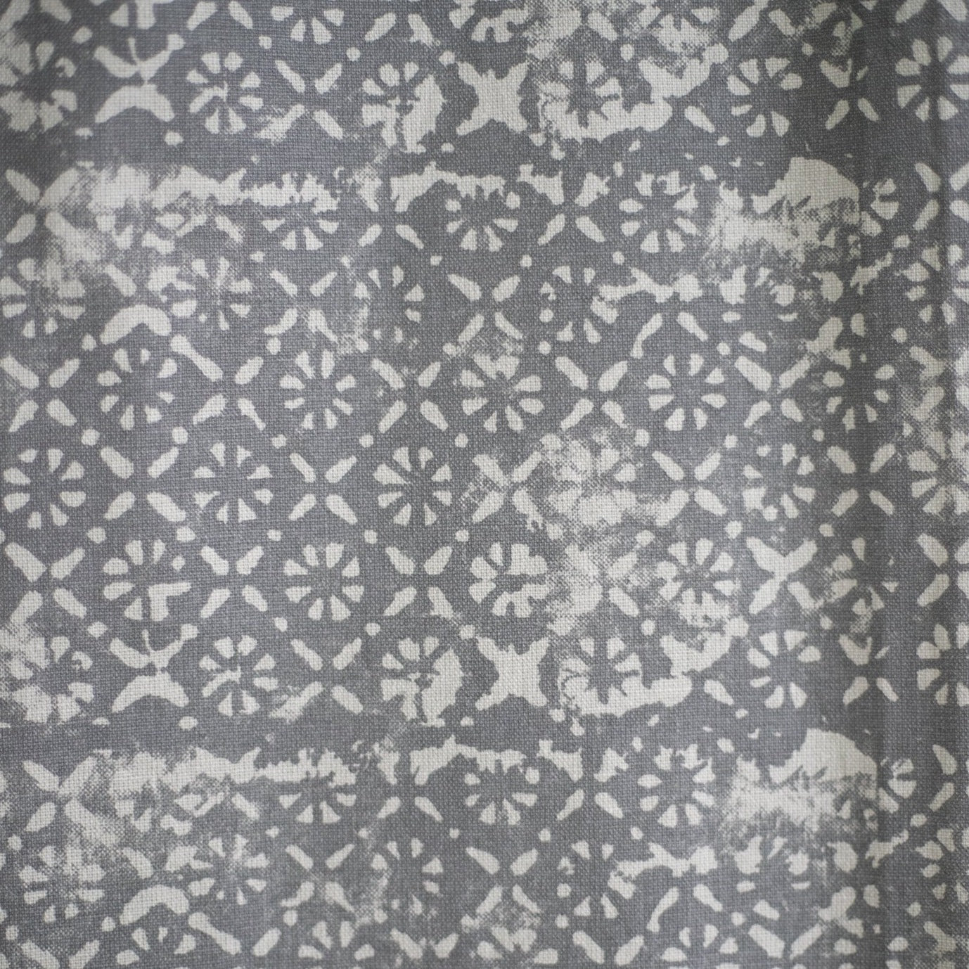 Gray shower curtain with white geometric and floral pattern throughout.