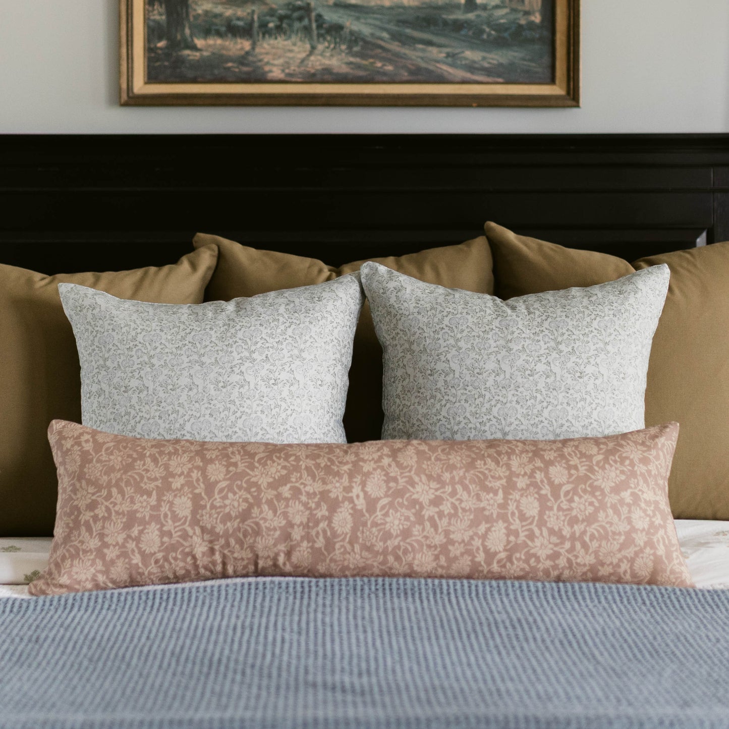 Lumbar throw pillow with rose damask pattern on bed with decorative pillows.