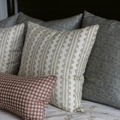 Linen pillow with vertical stripe and leaf pattern in cream and sage green, displayed with coordinating patterned pillows.