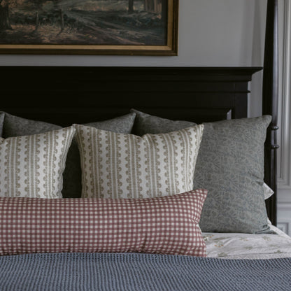 Blue textured lumbar pillow on bed with patterned and solid pillows against black headboard.
