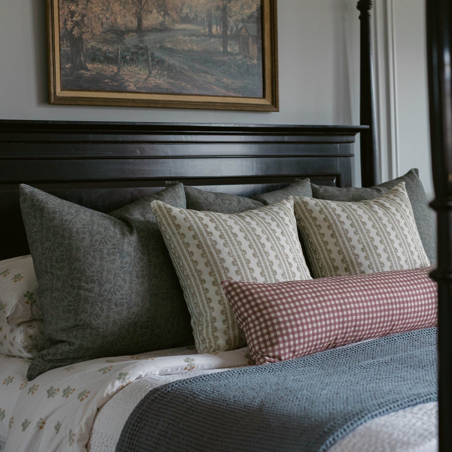 Blue textured throw pillow arranged with patterned pillows on a black bed frame.