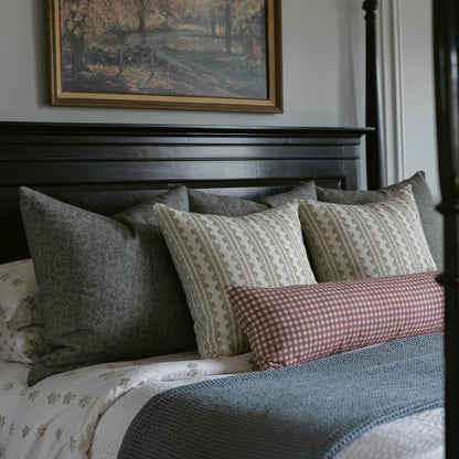 Blue textured throw pillow arranged with patterned pillows on a black bed frame.