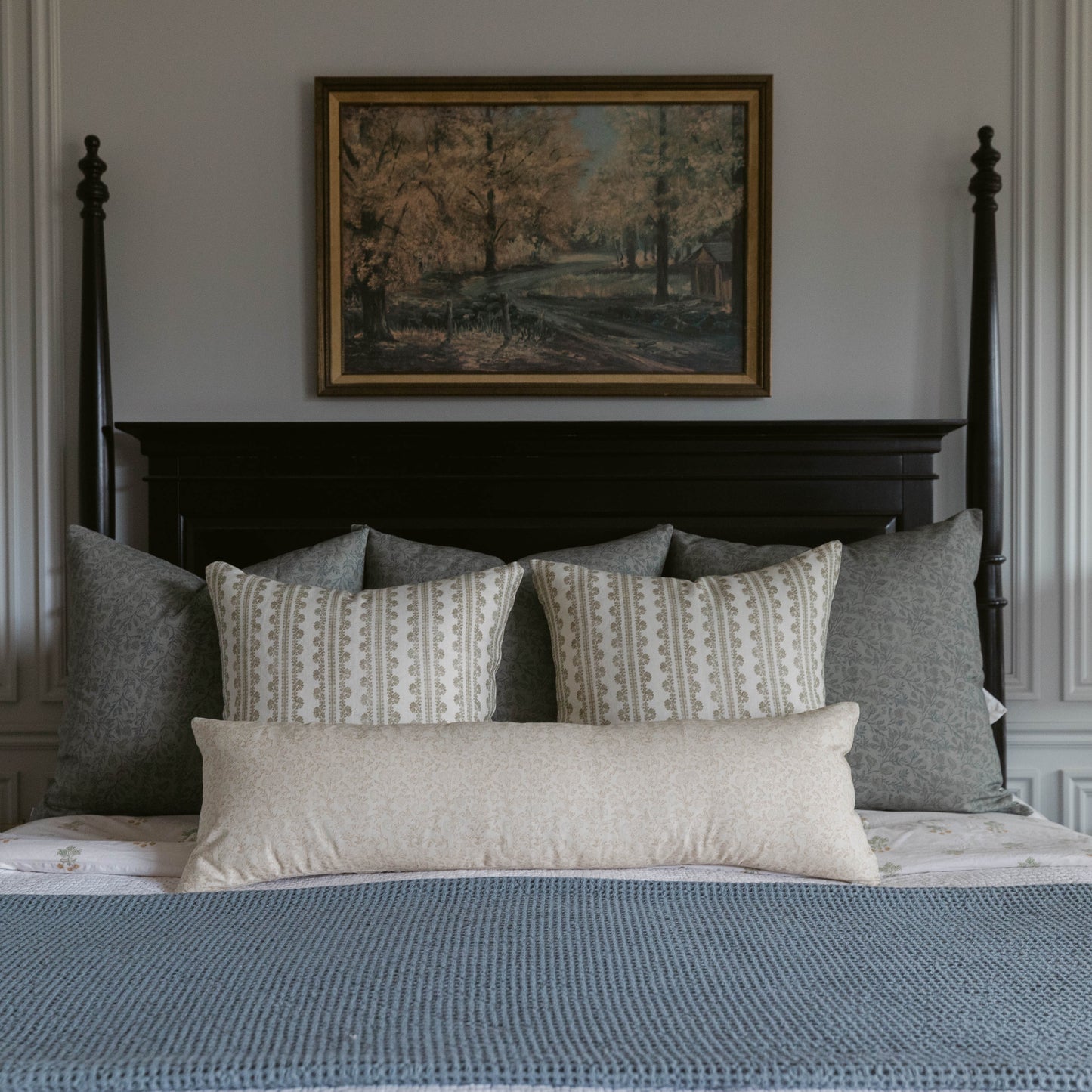 Beige linen lumbar pillow with geometric pattern displayed on bed with gray pillows and blue bedding.