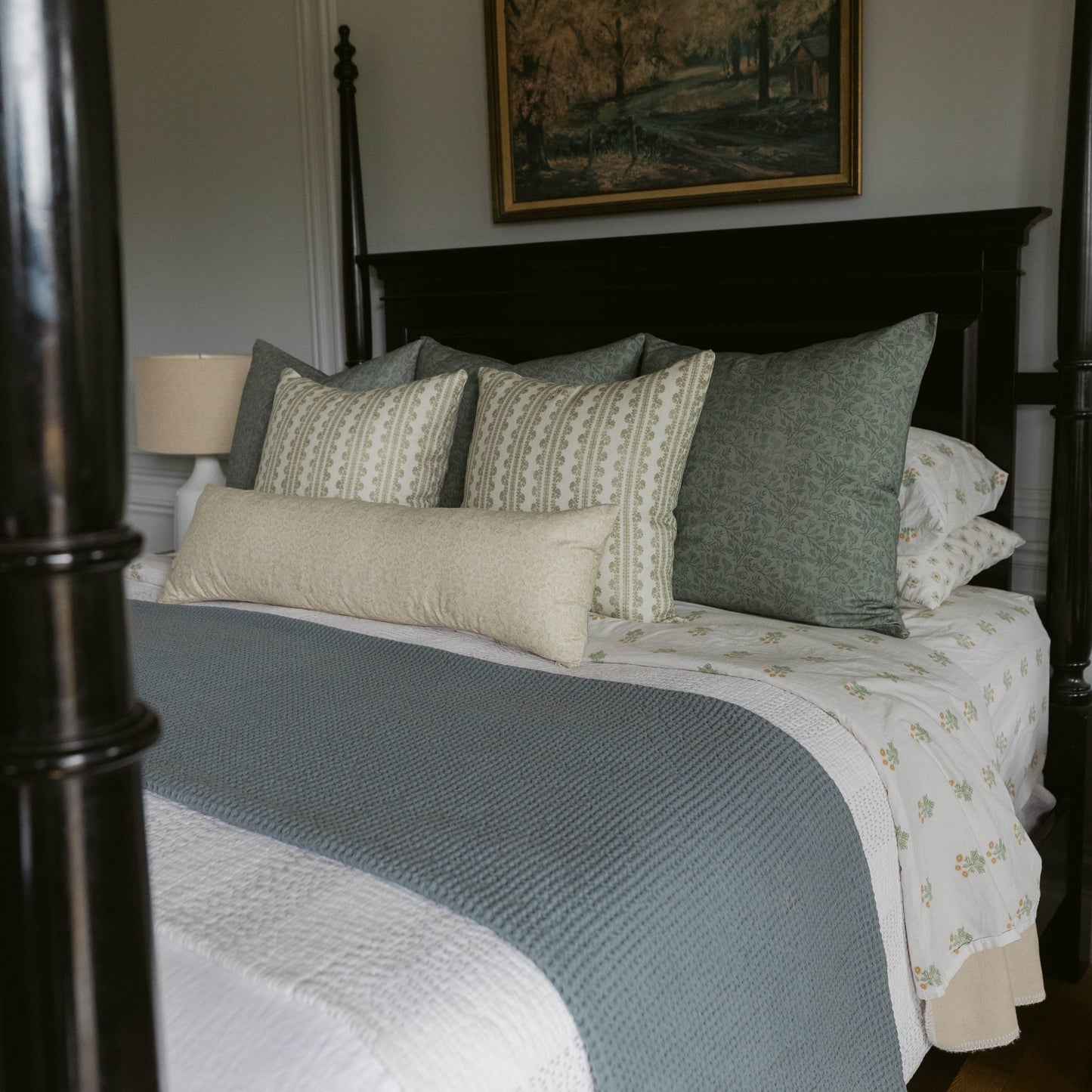 Arlo linen pillow in cream and sage green geometric patterns displayed on a black bedroom bed with matching bedding.
