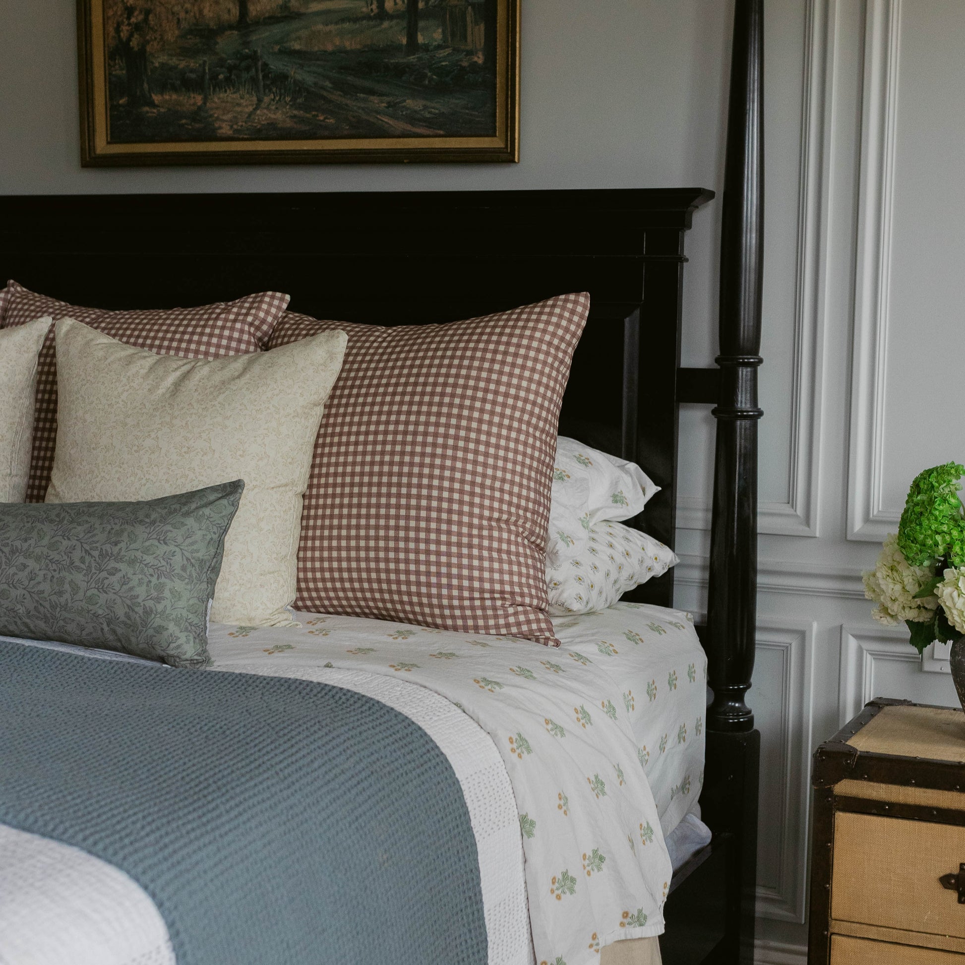 Rose gingham pillow cover in muted mauve and cream checkered pattern on bed with coordinating pillows.