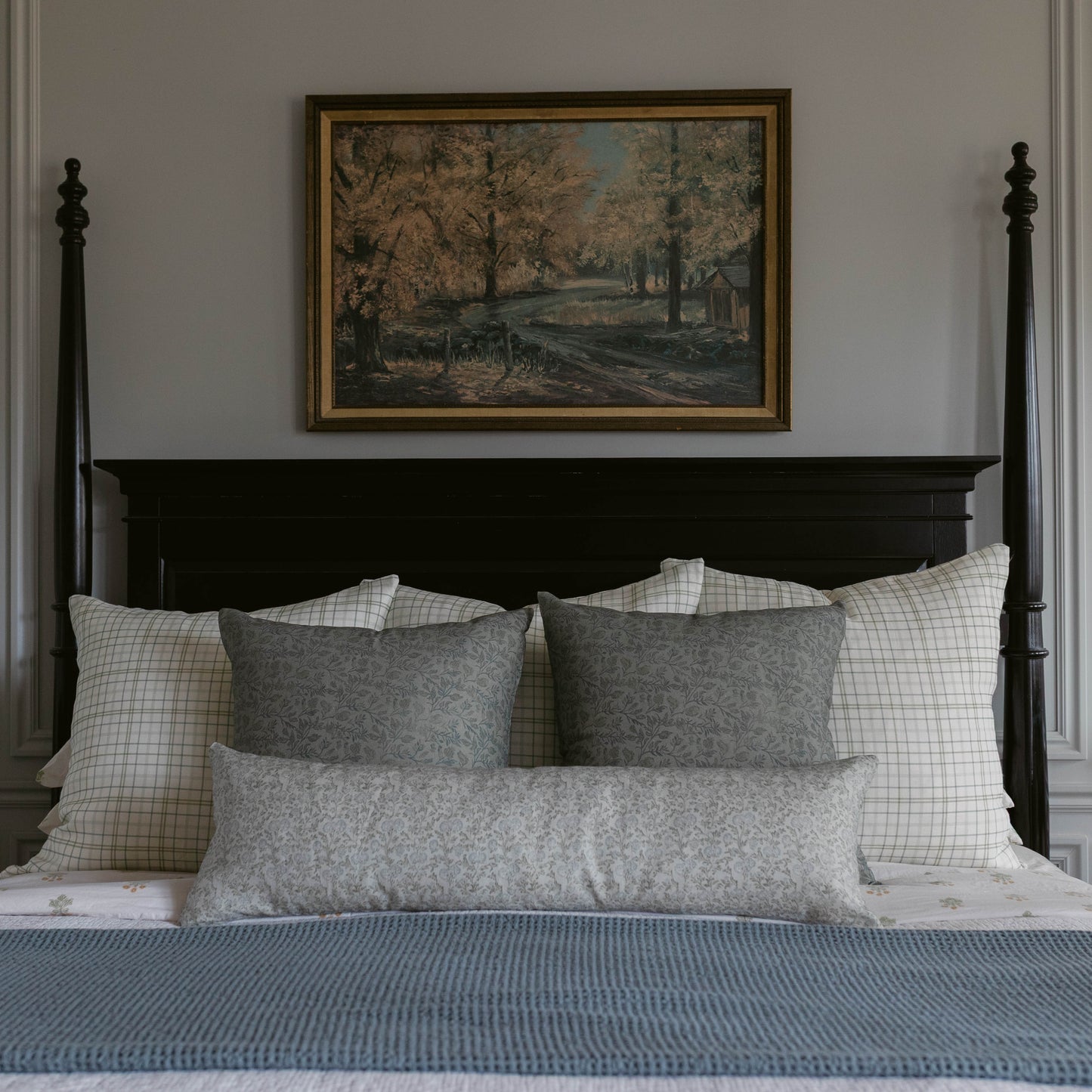 Blue lumbar pillow on bed with checkered and gray patterned pillows.