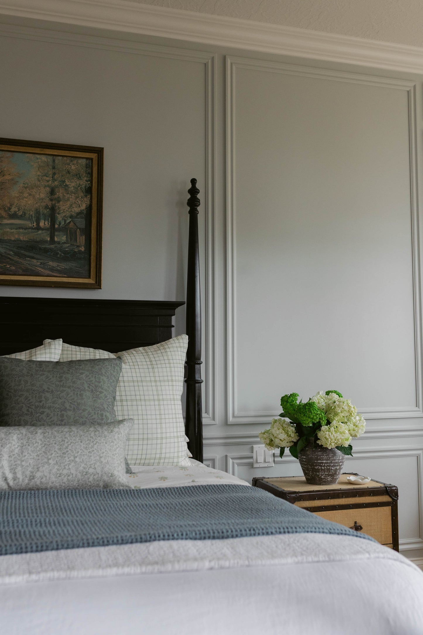 Beige linen pillow styled on a bed with white grid and gray patterned pillows.