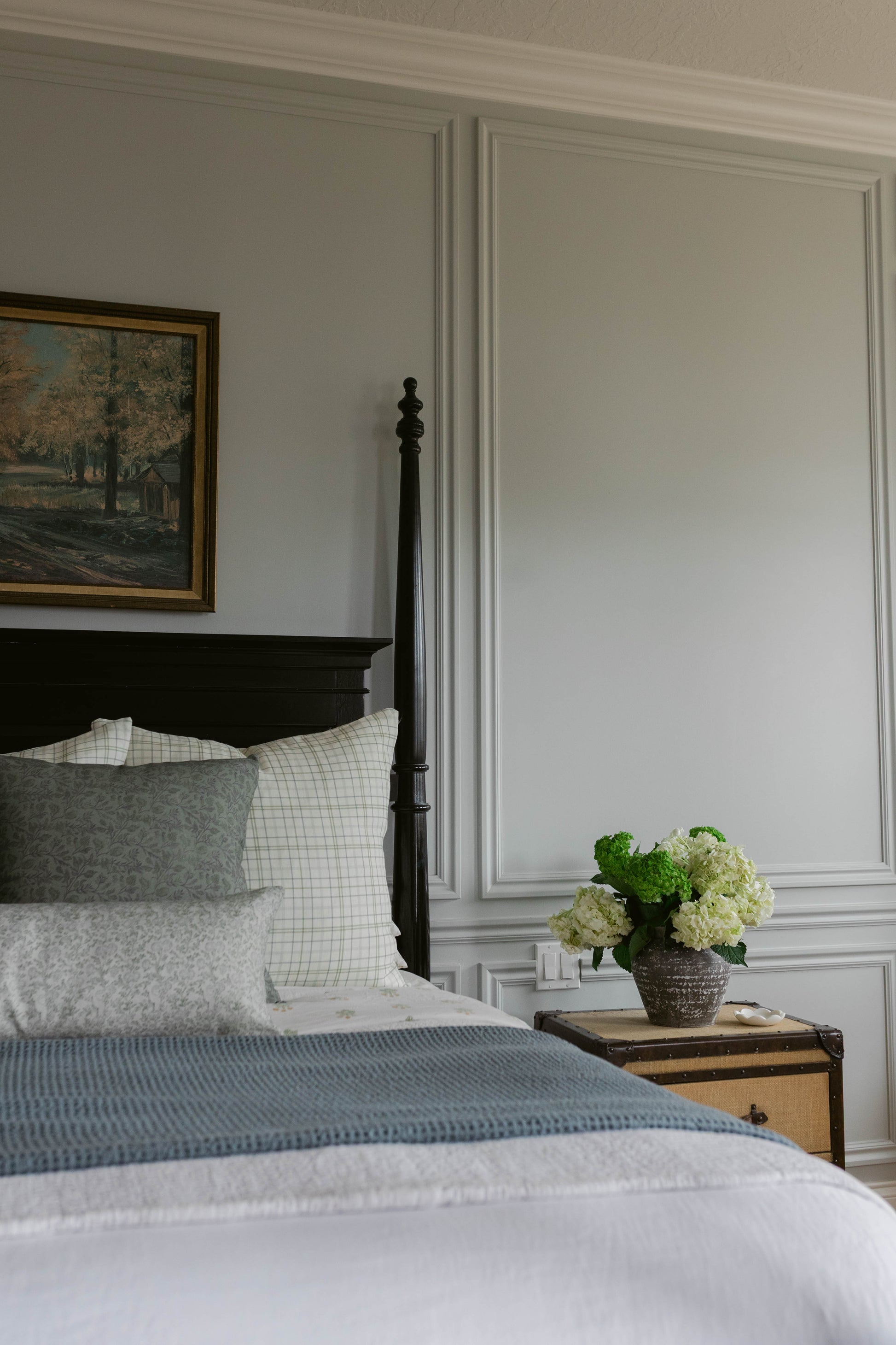 Beige linen pillow styled on a bed with white grid and gray patterned pillows.