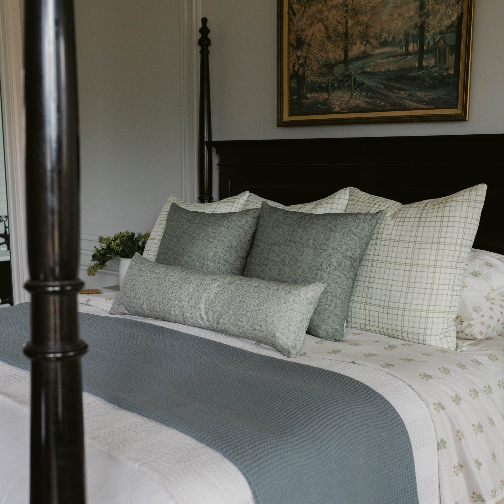 Blue-gray lumbar pillow styled on bed with matching pillows and white bedding.