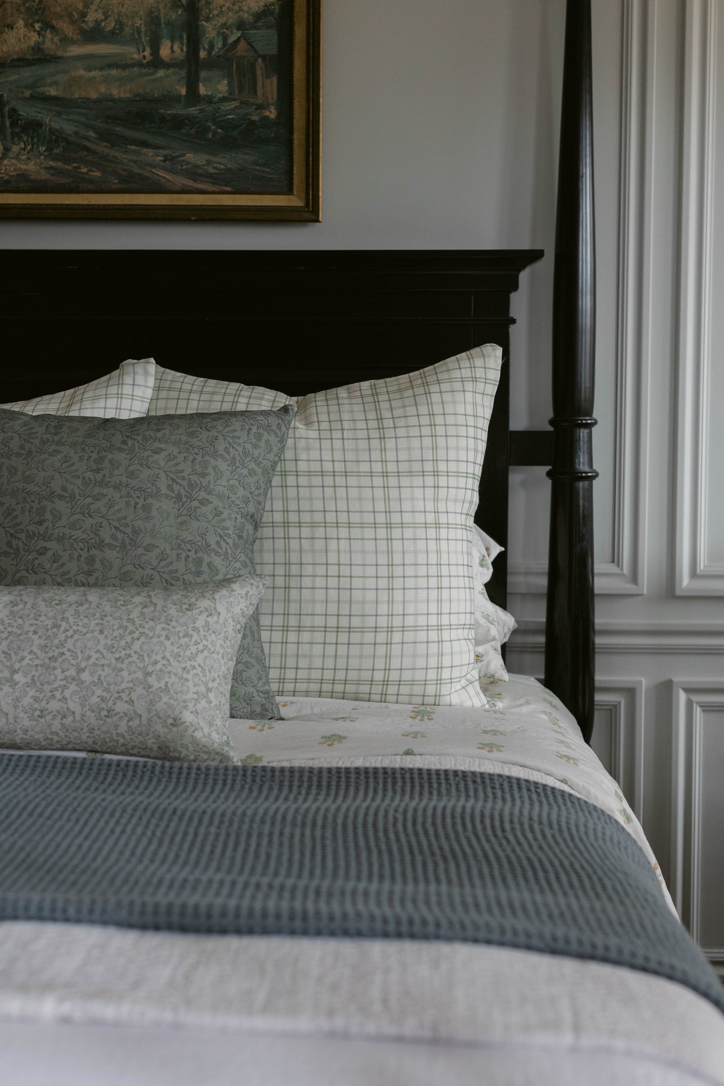 Rhodes linen pillow with green windowpane pattern displayed on black bed frame with coordinating bedding.