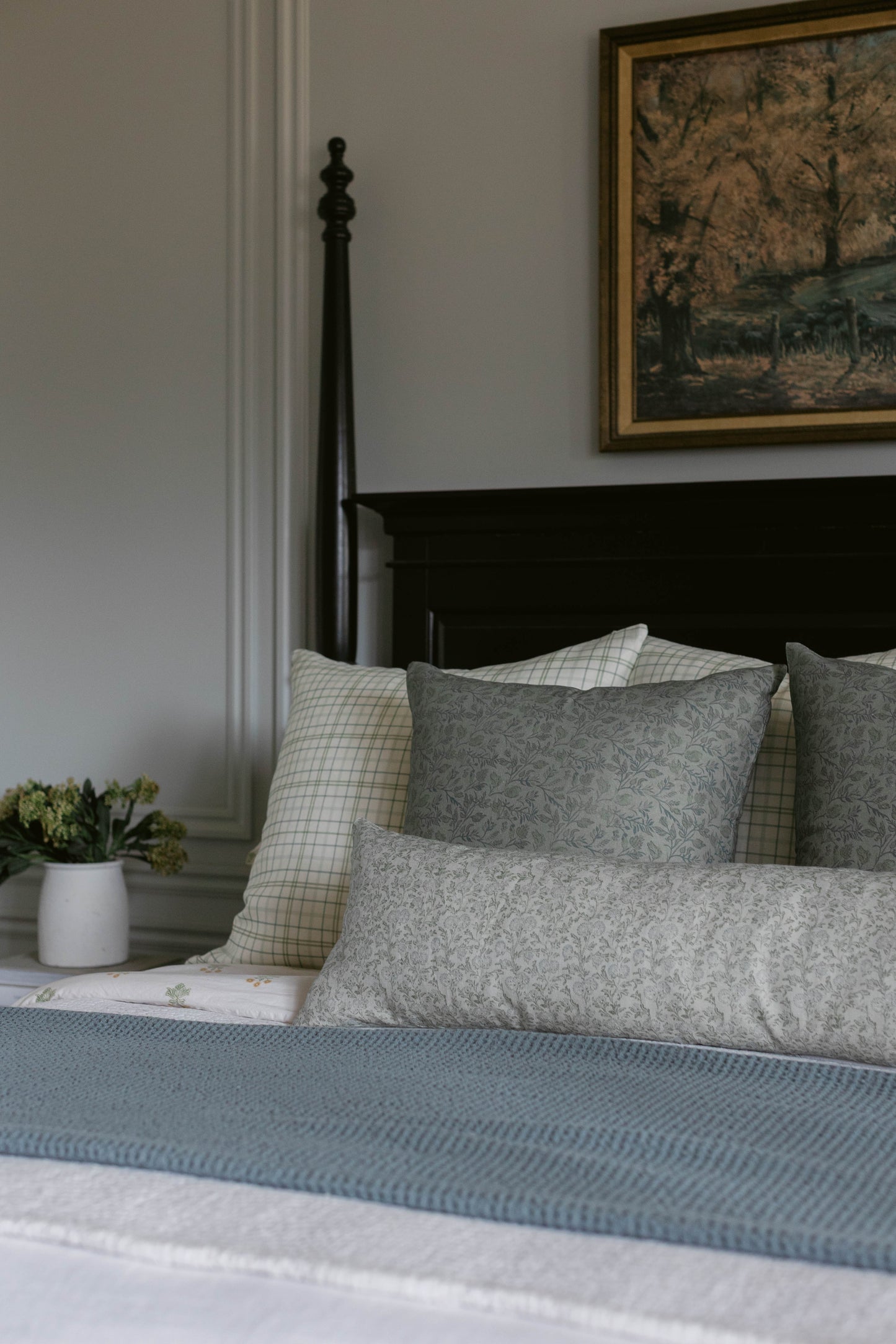 Gray patterned pillows and blue textured bedding on a black metal bed frame.