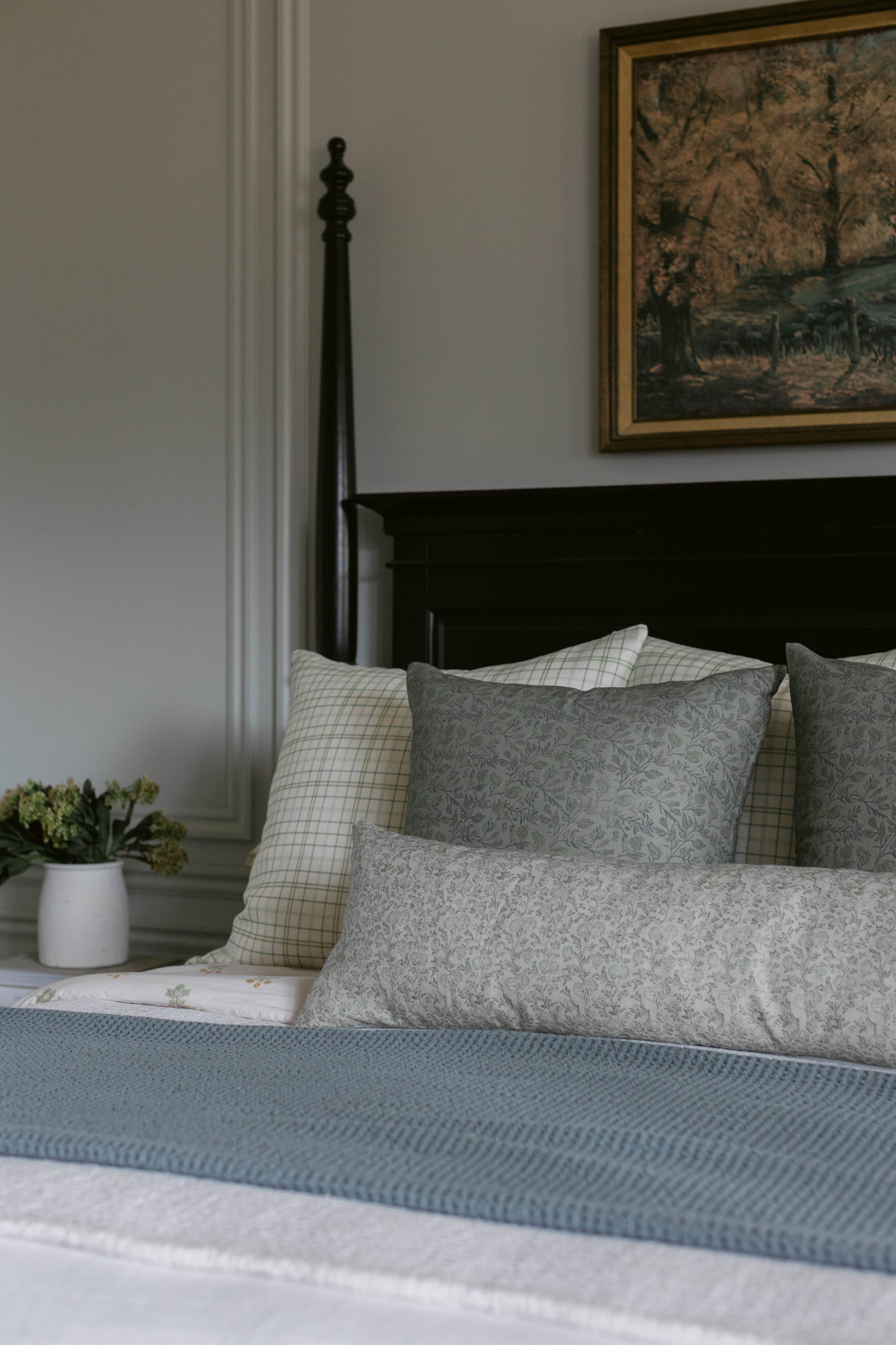Gray patterned pillows and blue textured bedding on a black metal bed frame.