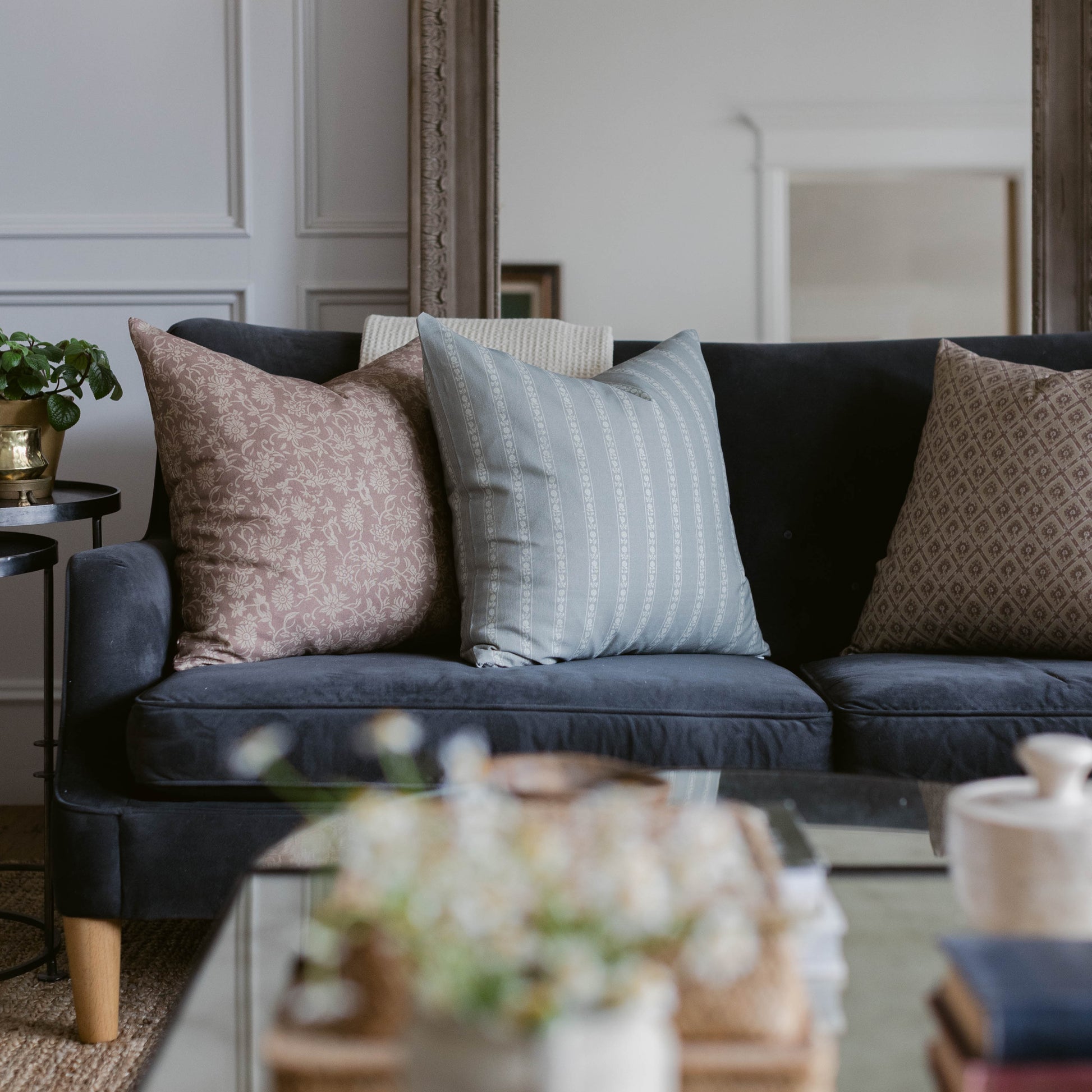 Dark sofa with four decorative pillows in pink floral, blue striped, black, and tan geometric patterns.