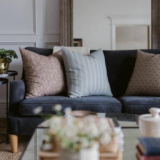 Dark sofa with four decorative pillows in pink floral, blue striped, black, and tan geometric patterns.