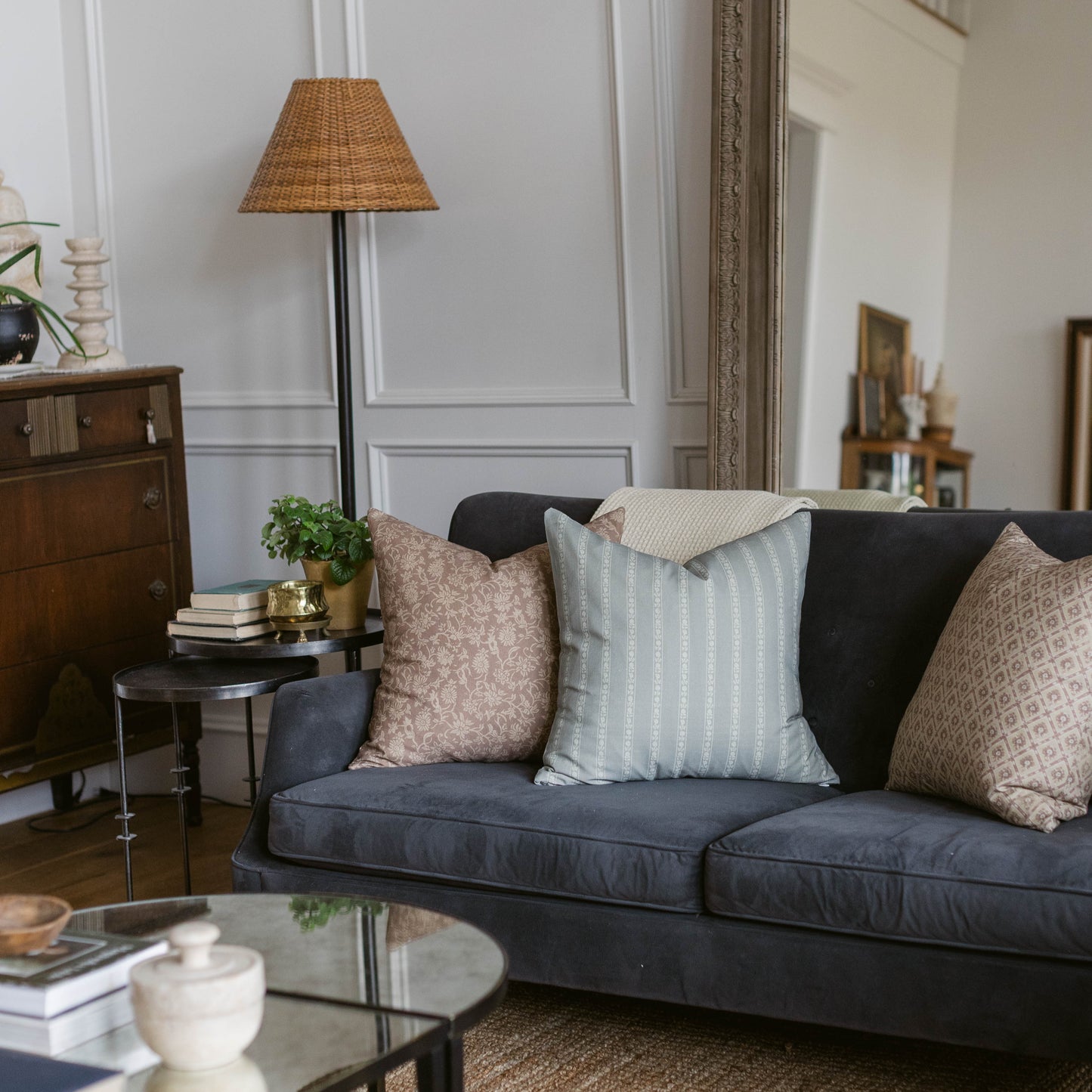 Four decorative throw pillows in neutral tones with various patterns displayed on a dark gray sofa.