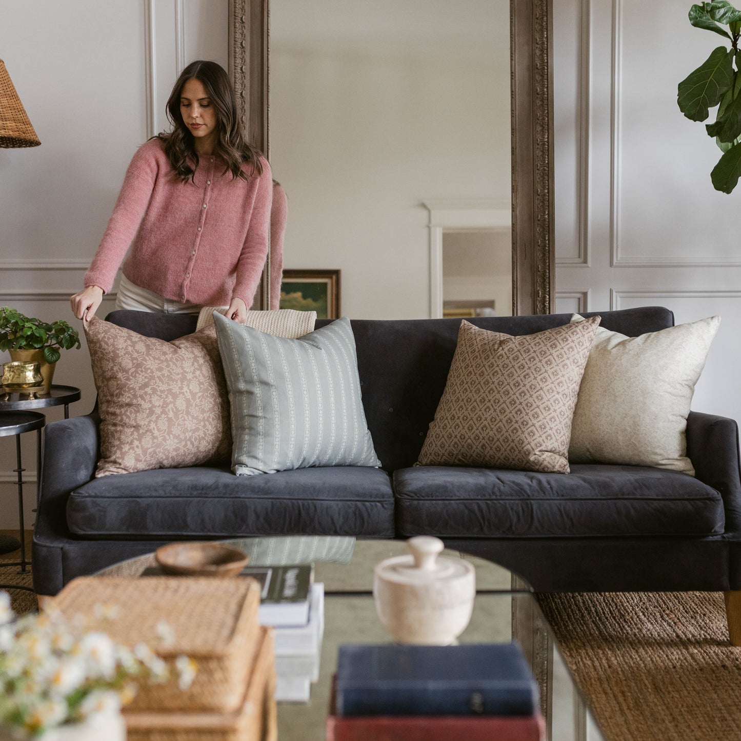 Four decorative pillows in neutral tones displayed on a dark sofa, ranging from 18" to 22" in size.