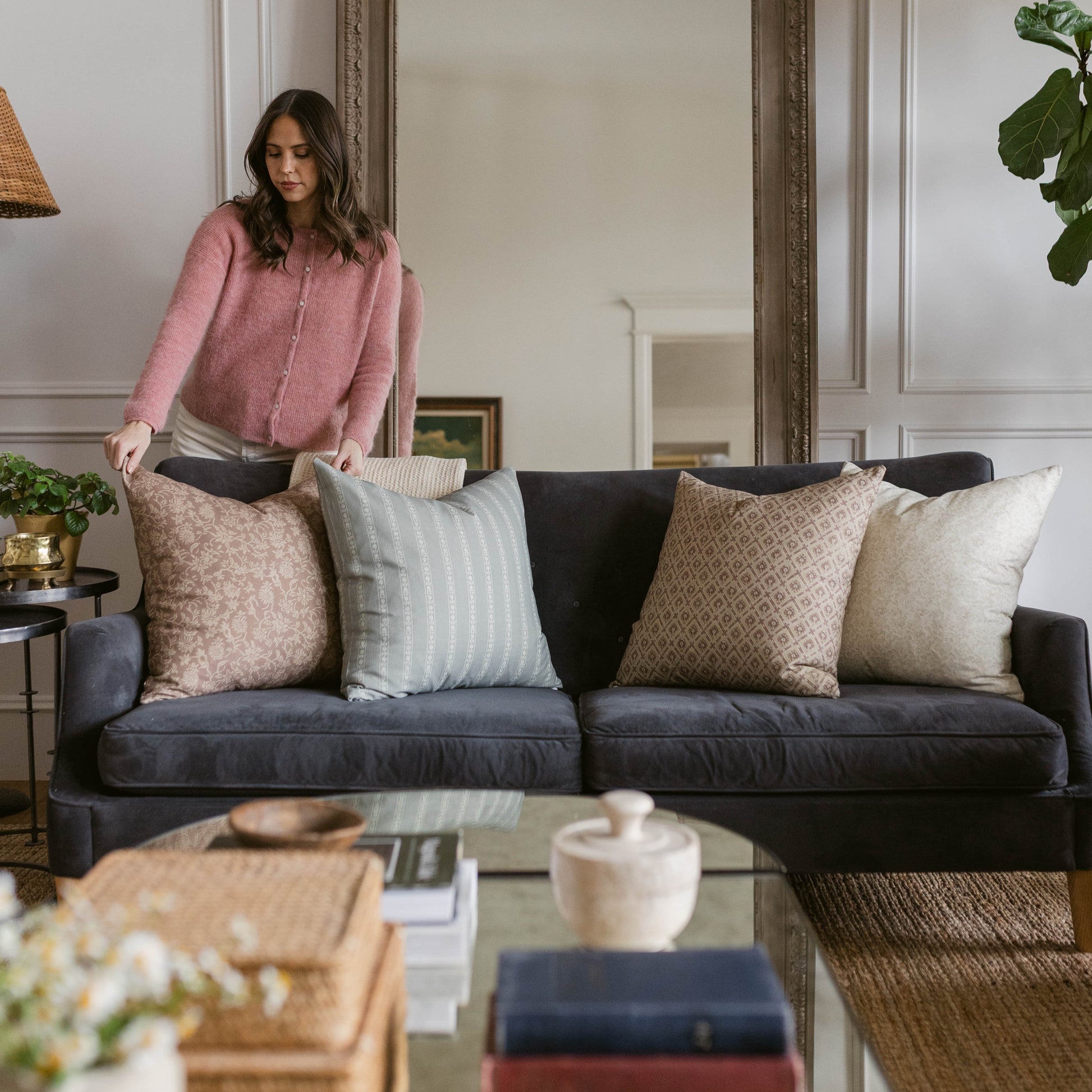 Four decorative pillows in neutral tones displayed on a dark sofa, ranging from 18" to 22" in size.