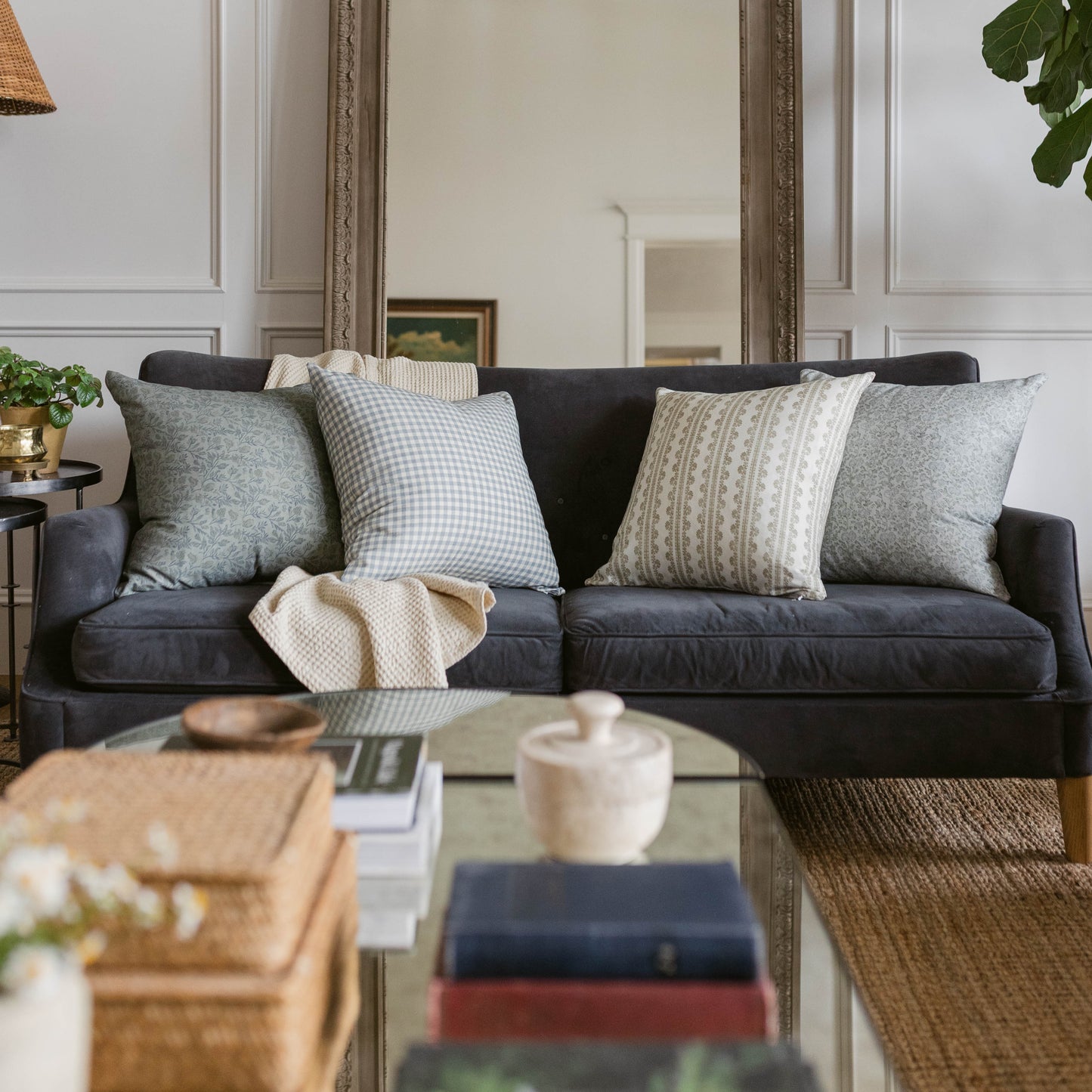 Four decorative pillows in various patterns displayed on a black sofa in a living room setting.