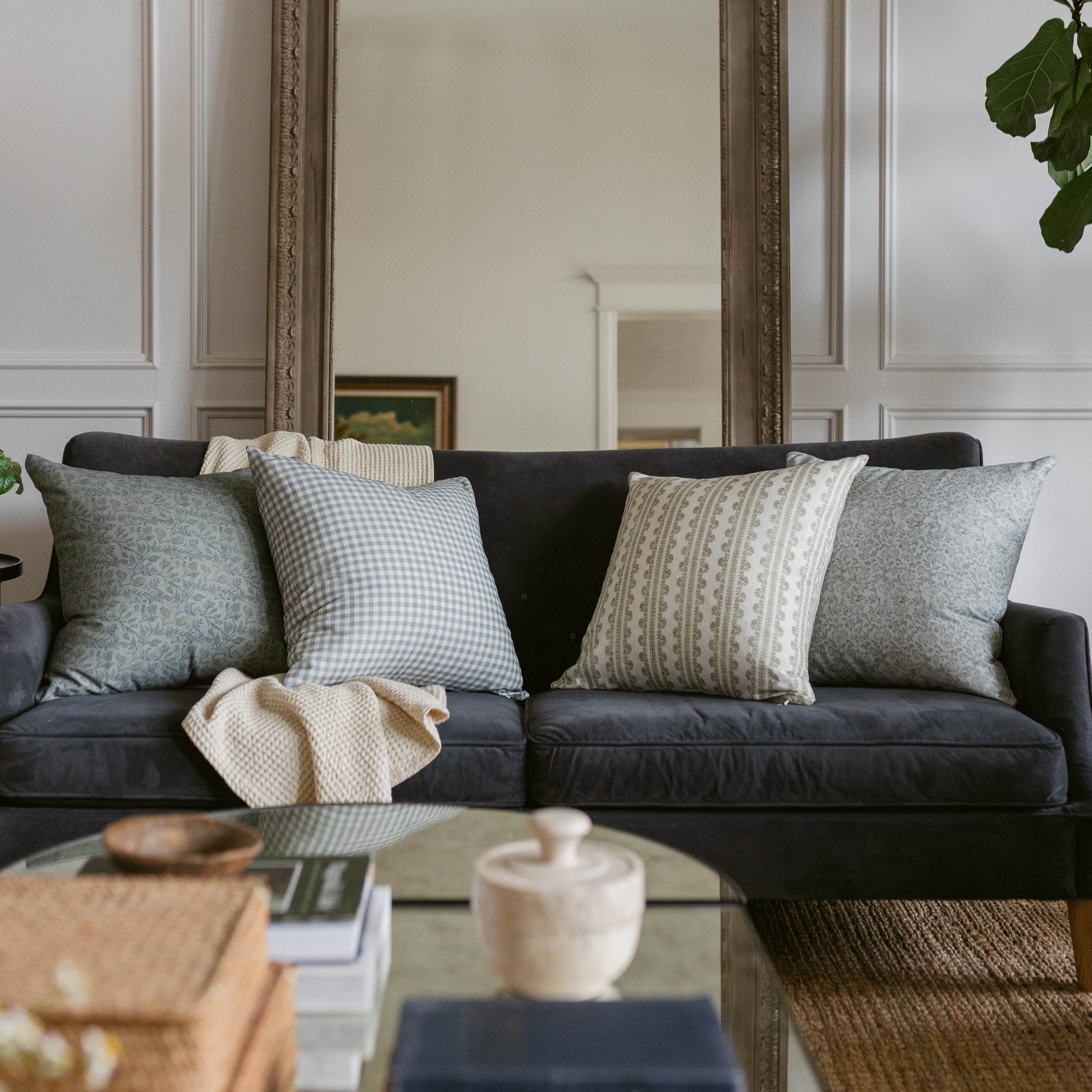 Linen pillow in neutral tones displayed on a black sofa with decorative patterns and textures.