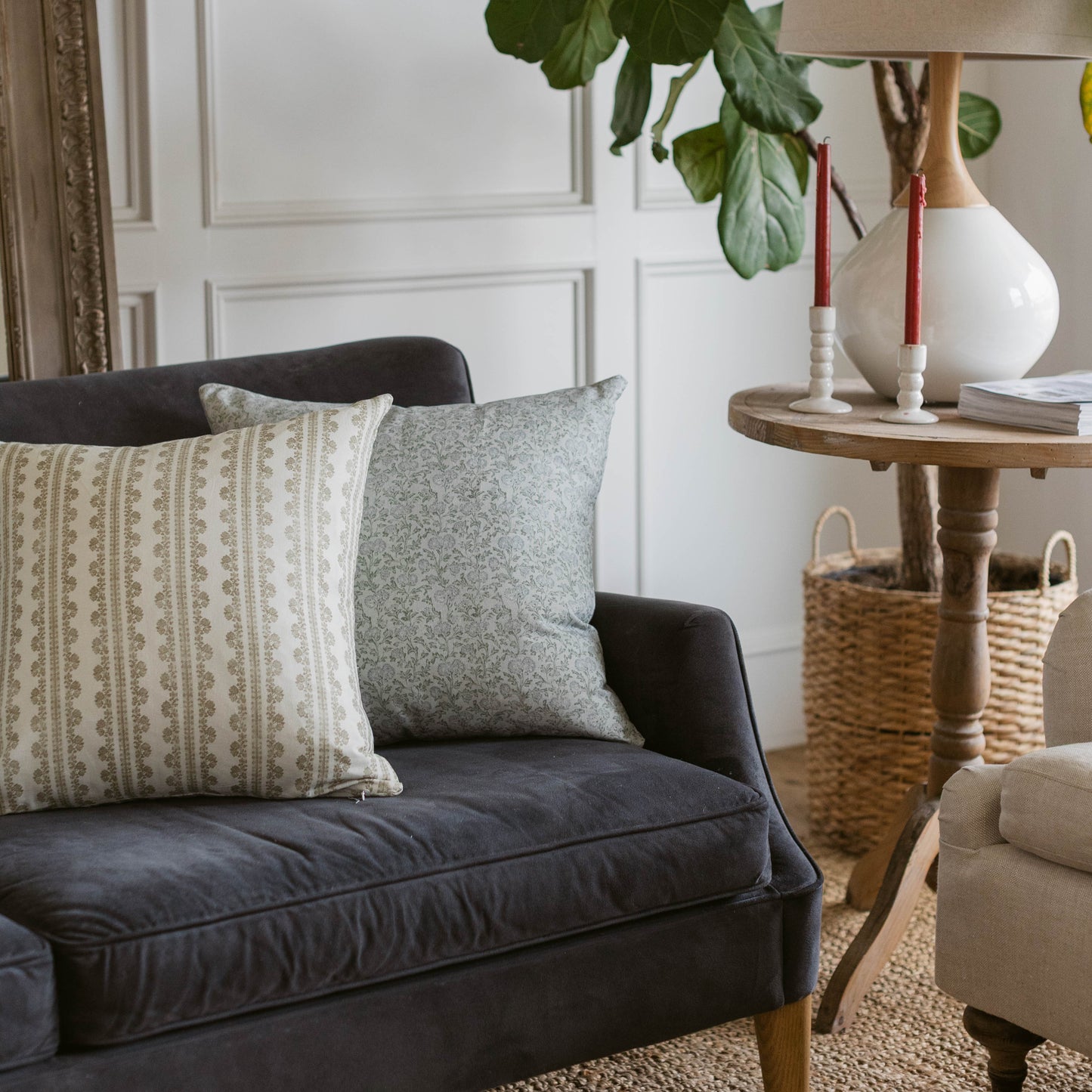 Gray linen pillow with textured weave displayed on black sofa next to patterned cream pillow.