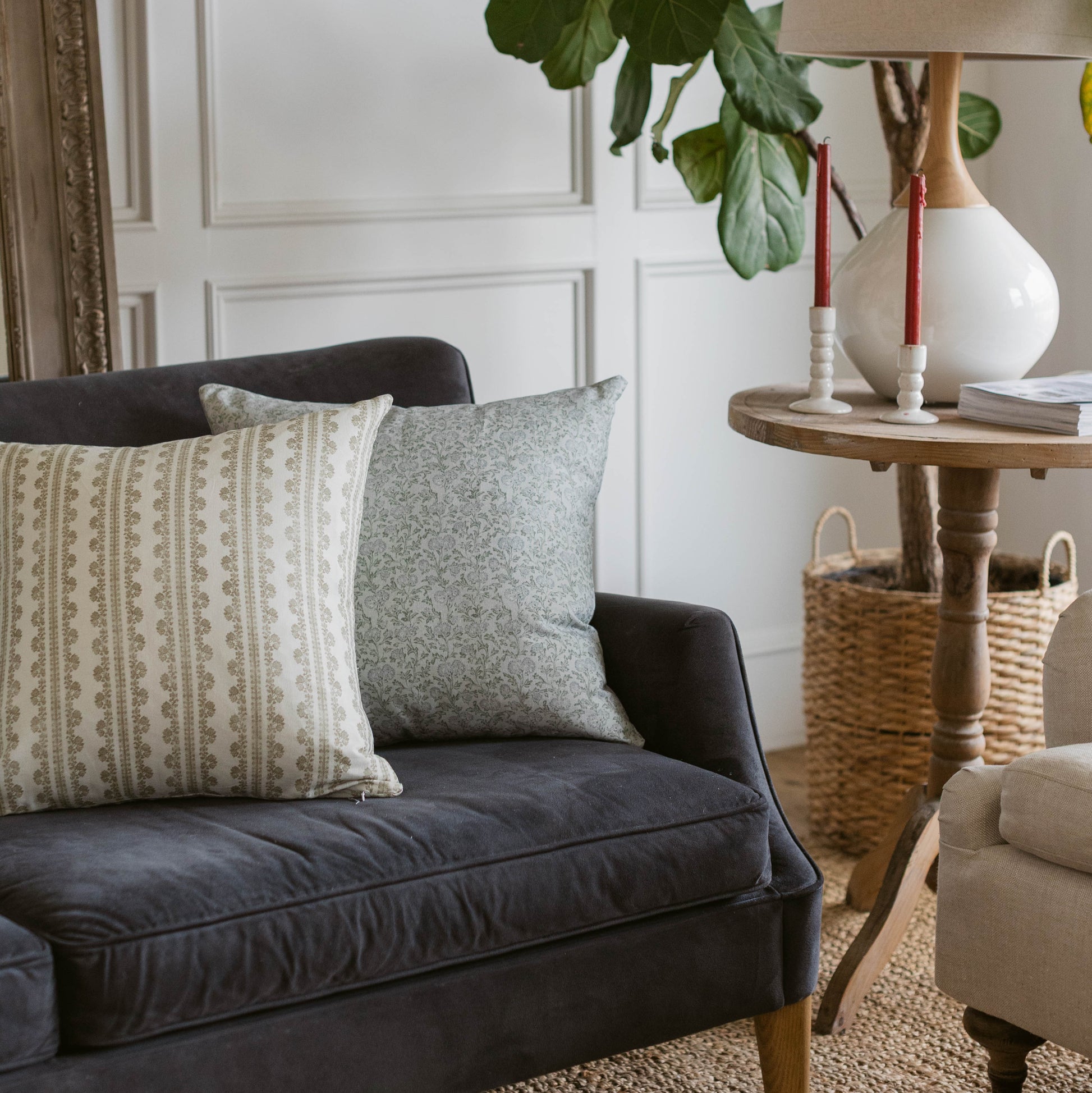 Gray linen pillow with textured weave displayed on black sofa next to patterned cream pillow.
