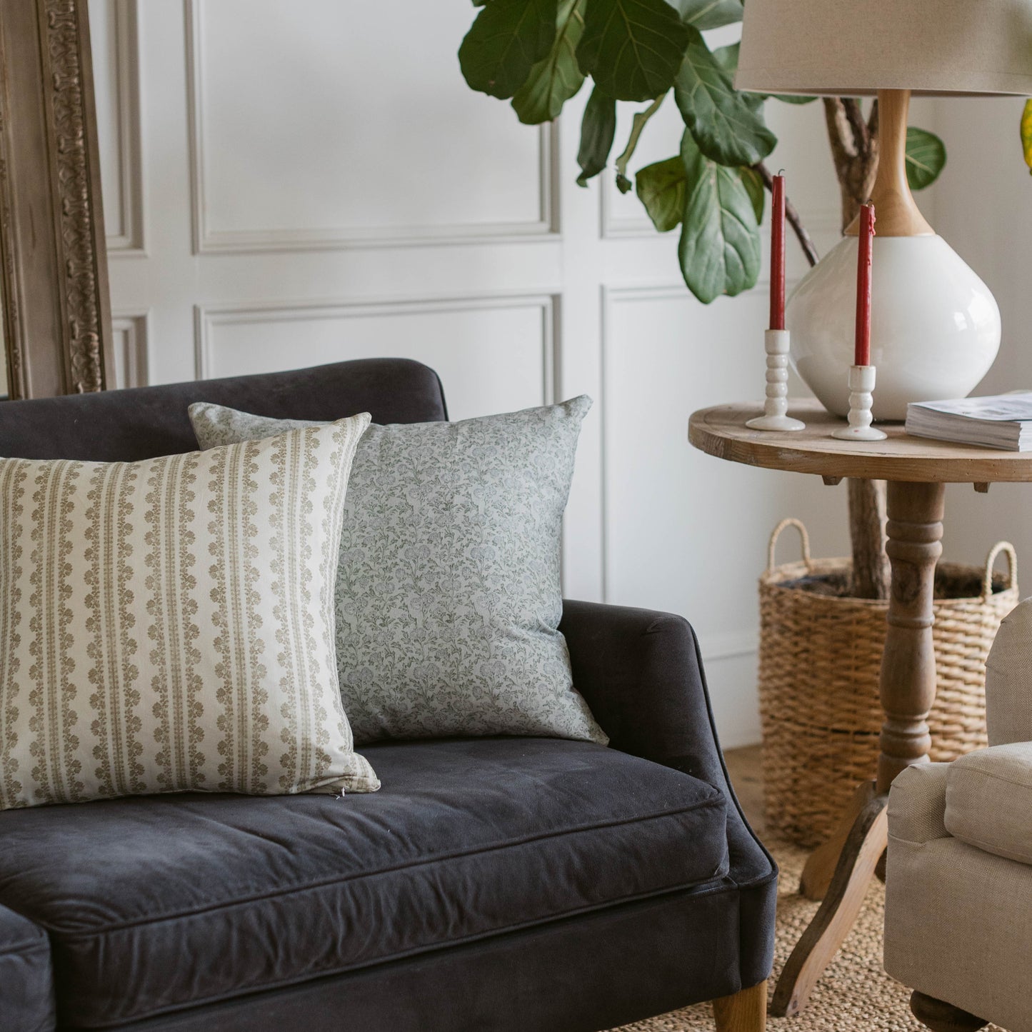 Two decorative pillows in cream and gray patterns displayed on a dark upholstered chair.
