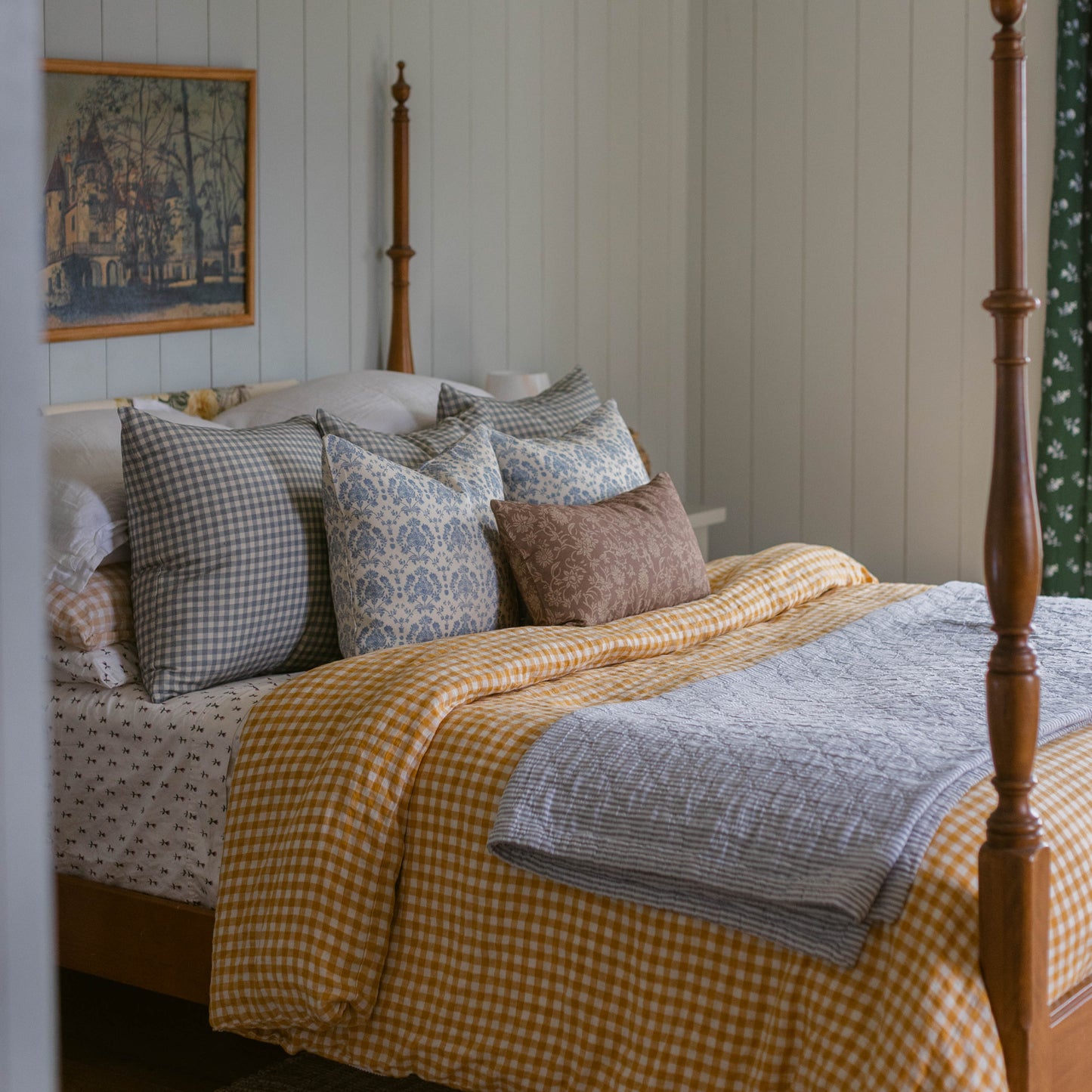 Dusty blue gingham pillows displayed on a wooden bed with coordinating bedding.