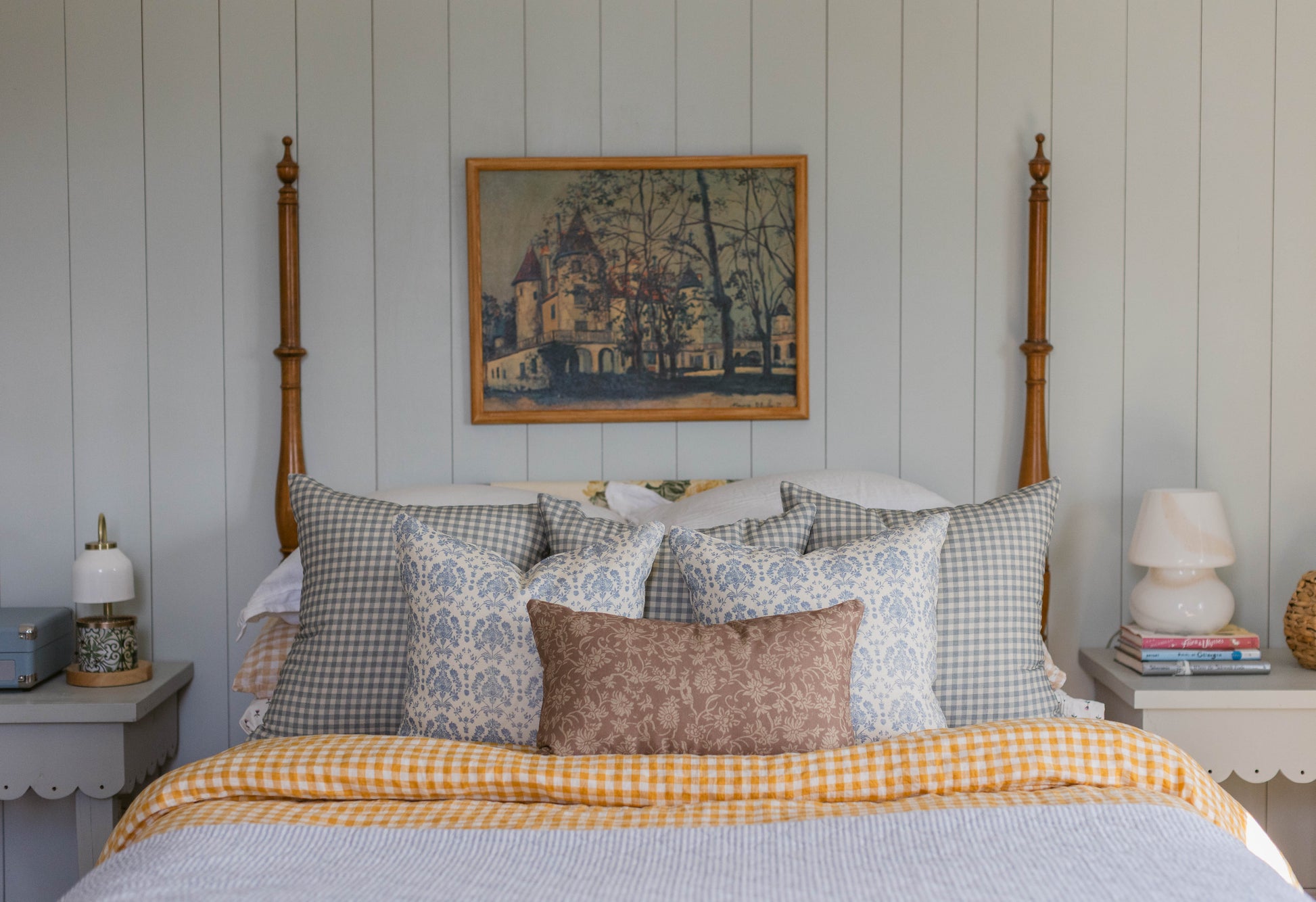 Double-sided linen pillow in cream and gray gingham pattern with coordinating patterned pillows on a bed.