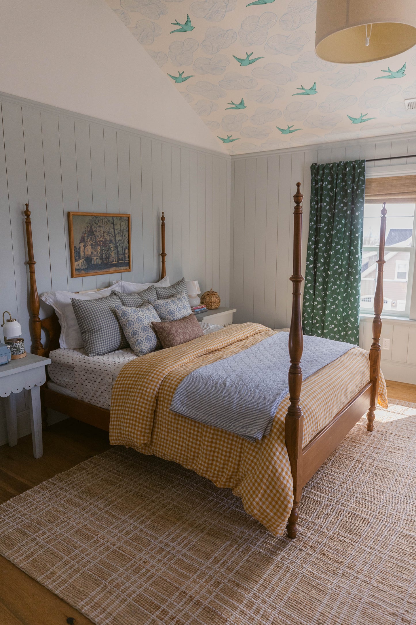 Linen pillow with blue and tan flying birds pattern displayed on bed with yellow gingham bedding in bedroom setting.