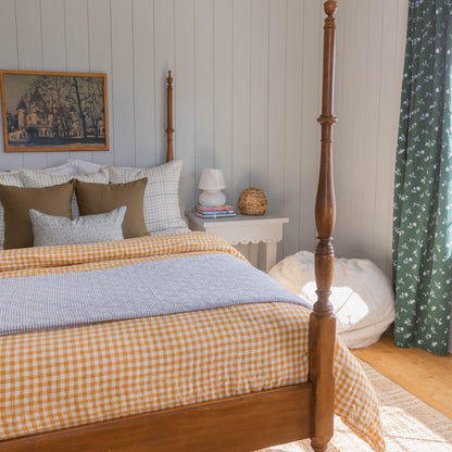 Wooden four-poster bed with turned finials and tall posts in a bedroom setting.