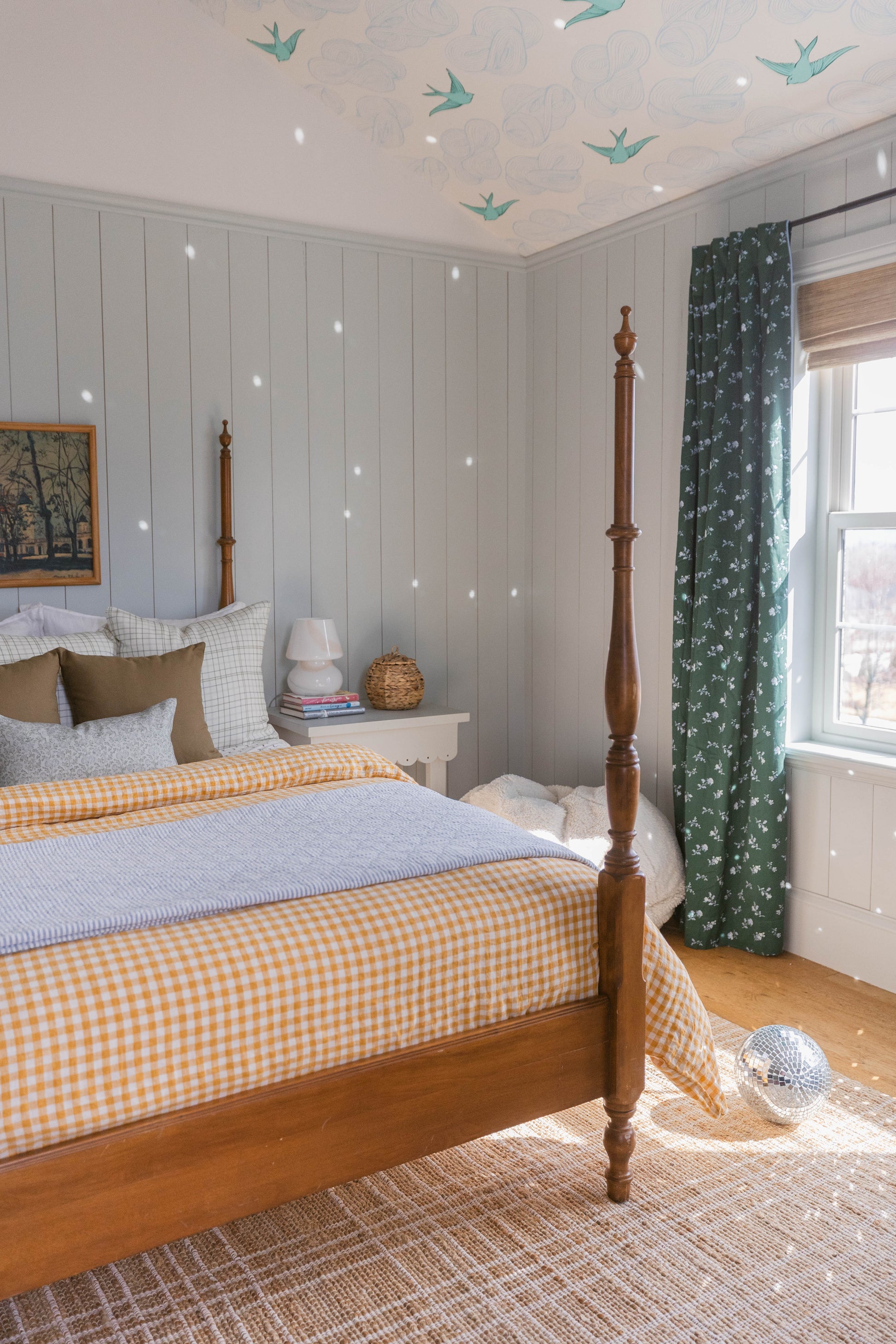 Beige linen pillow with subtle texture displayed on a four-poster bed styled with checkered and striped bedding.