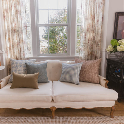 Cream upholstered sofa with wooden legs styled with patterned throw pillows in a living room setting.