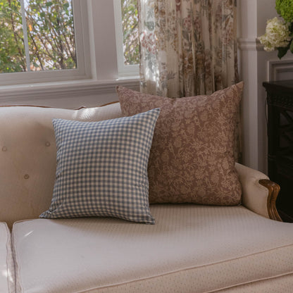 Dusty blue and white gingham checkered pillow displayed on a cream upholstered sofa.