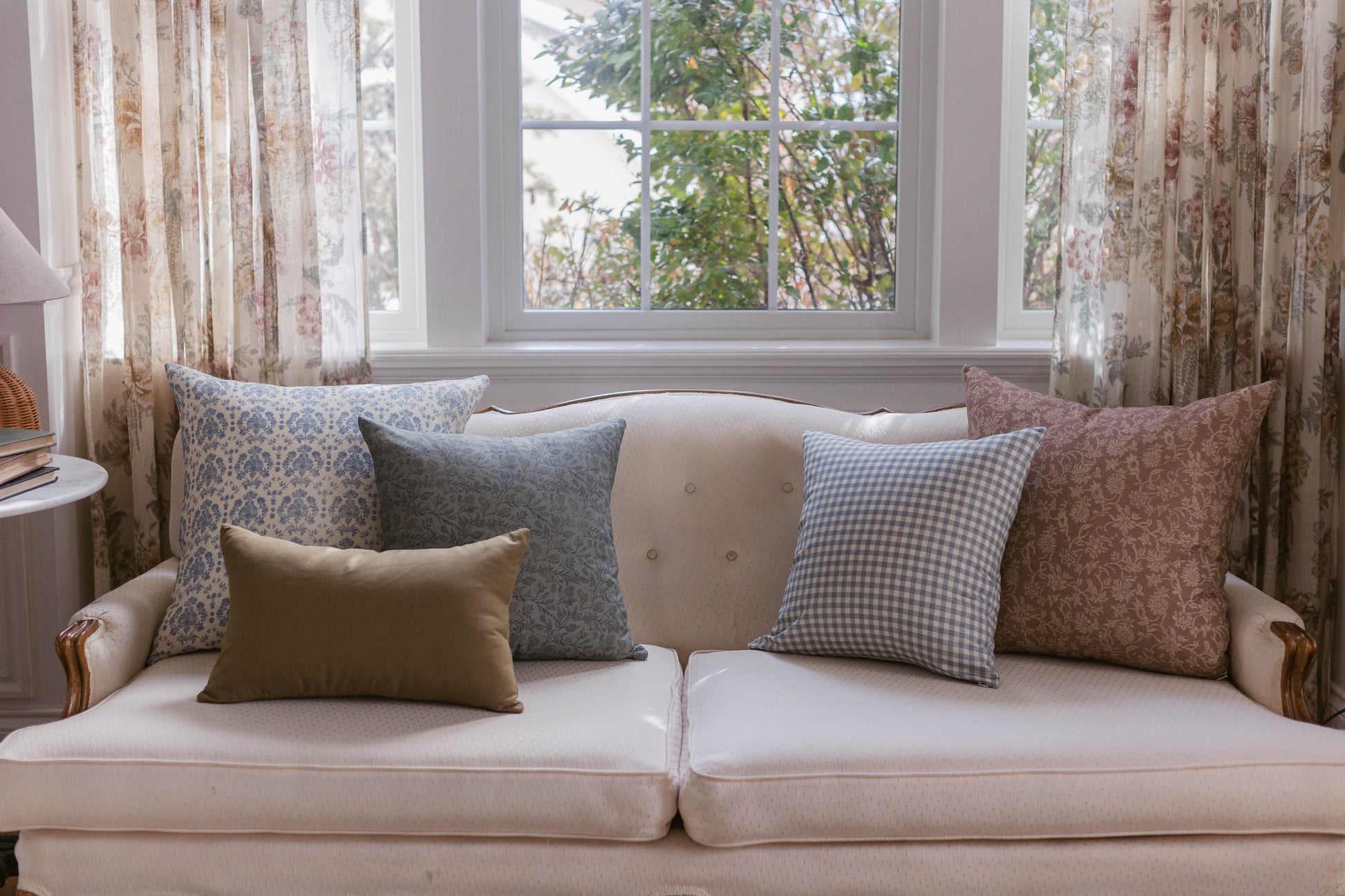 Blue patterned square pillow displayed on a beige sofa with coordinating decorative pillows.