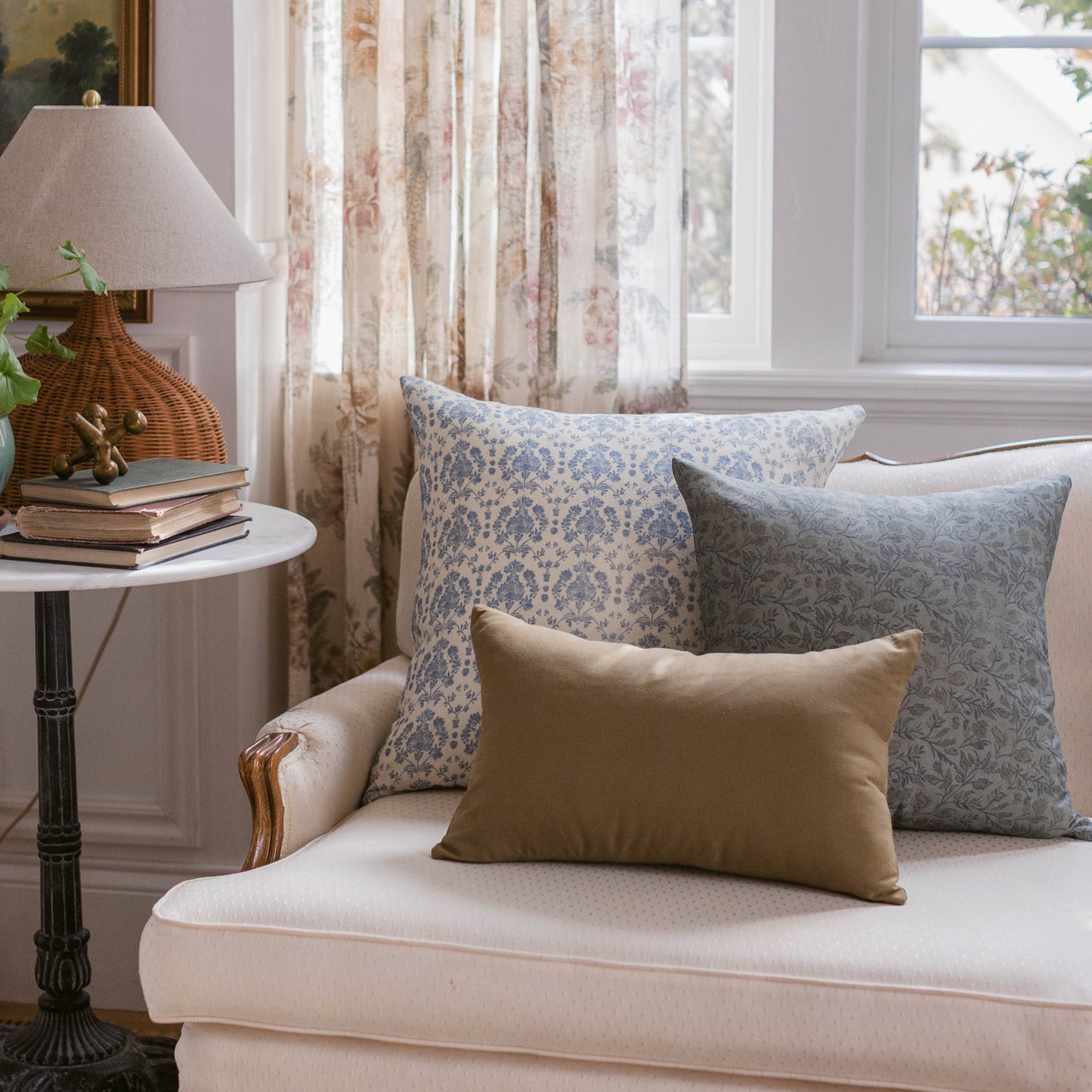 Blue and white patterned lumbar pillow displayed on a cream upholstered chair with coordinating pillows.