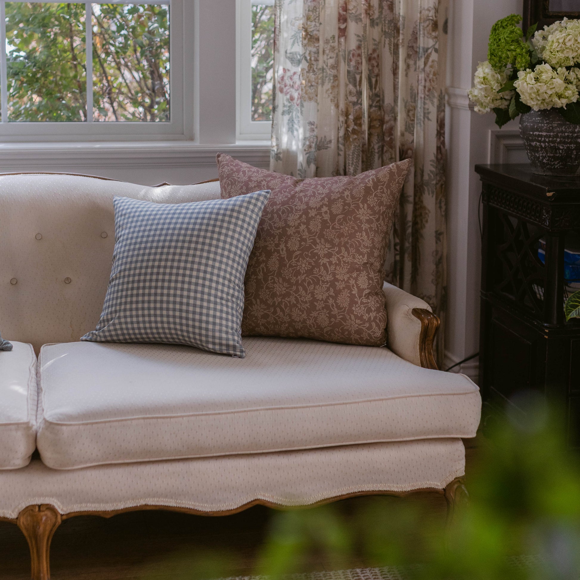 Dusty blue gingham pillow on cream upholstered sofa with brown damask pillow.