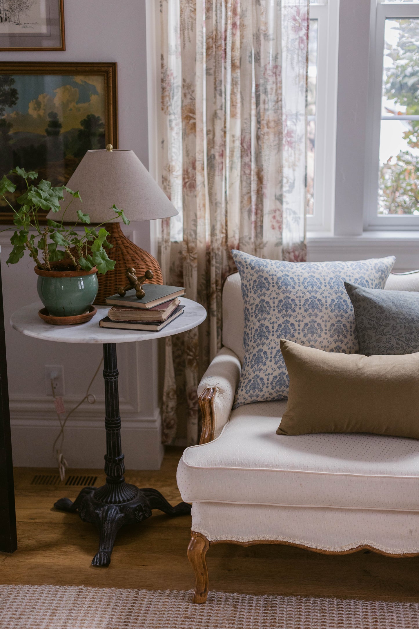 Rectangular linen pillow with blue damask pattern, displayed on cream-colored upholstered chair in living room setting.