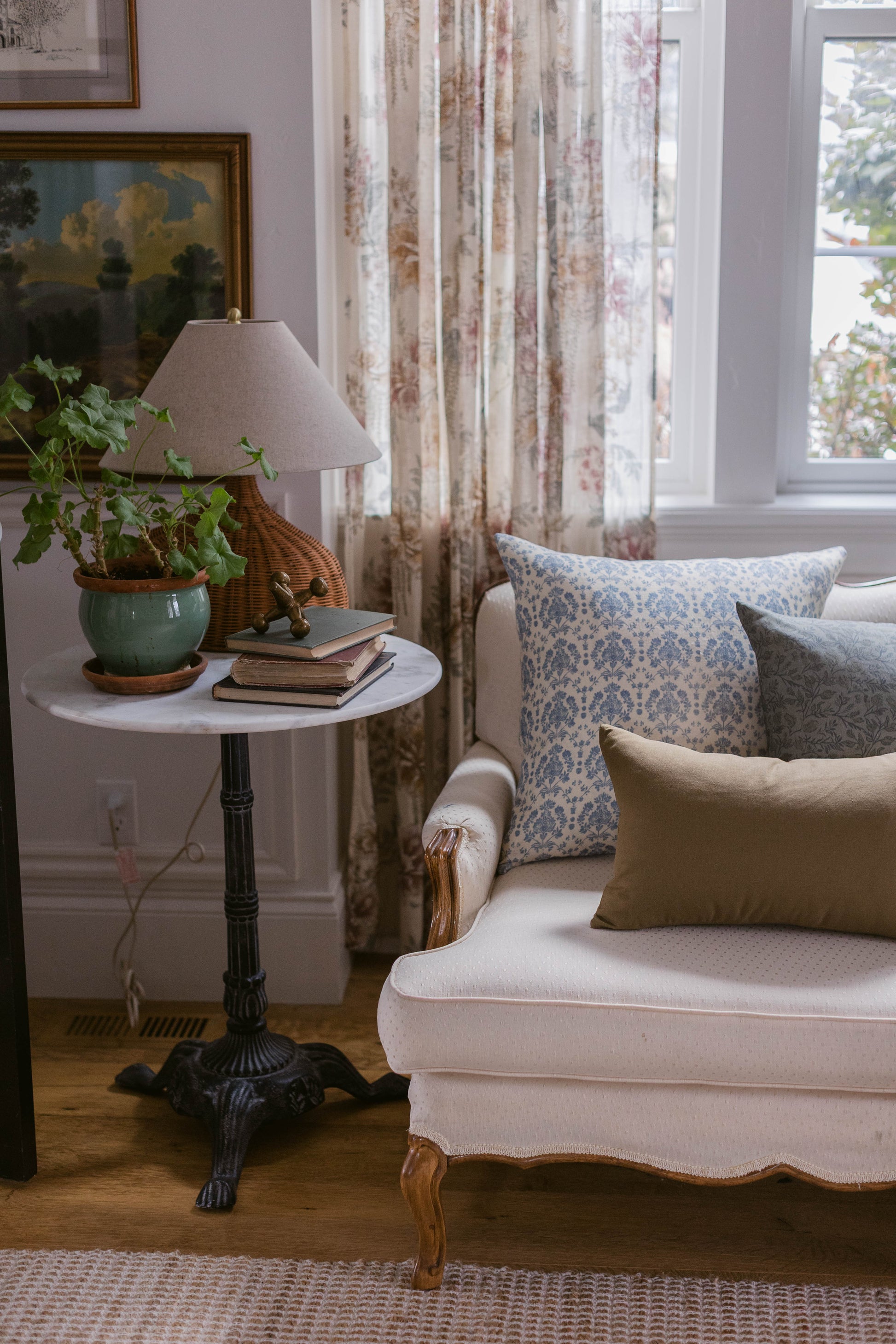 Rectangular linen pillow with blue damask pattern, displayed on cream-colored upholstered chair in living room setting.