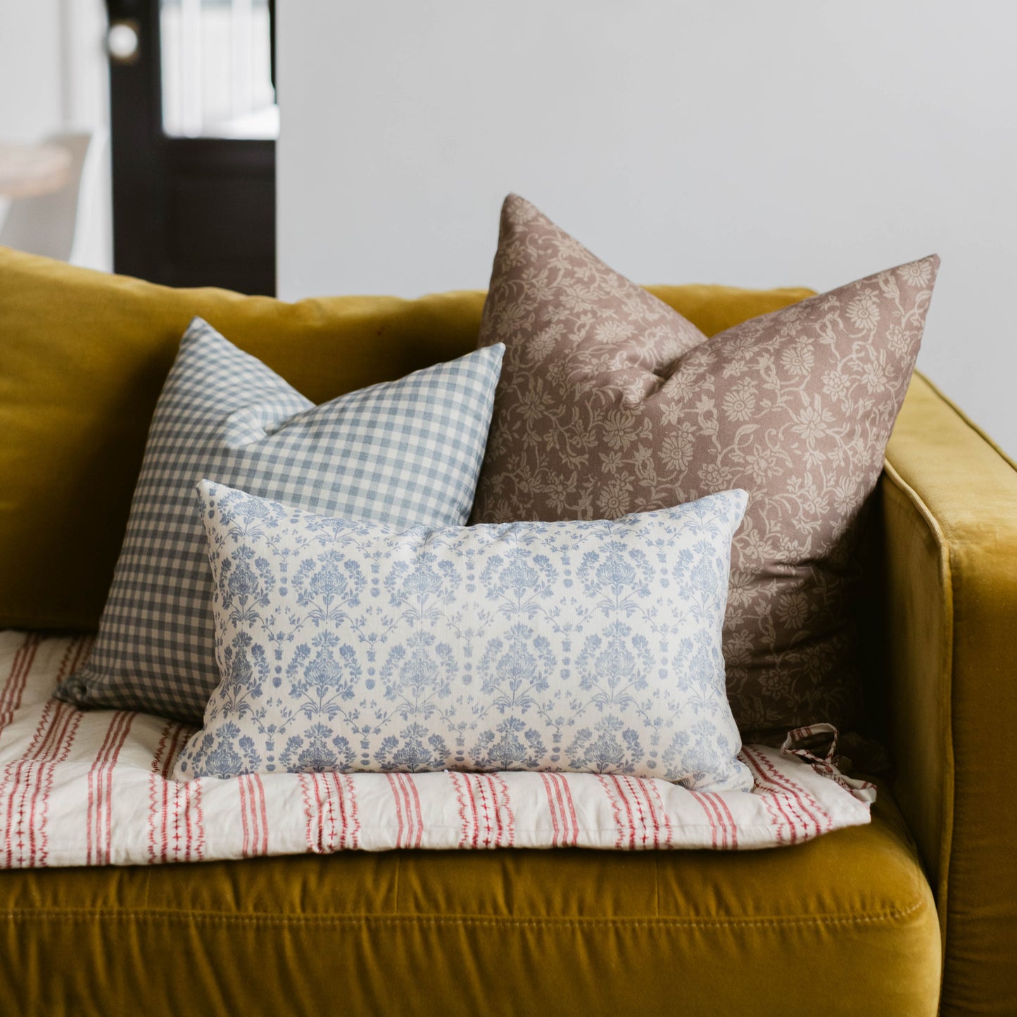 Blue and white damask patterned lumbar pillow displayed on a mustard yellow sofa with coordinating decorative pillows.