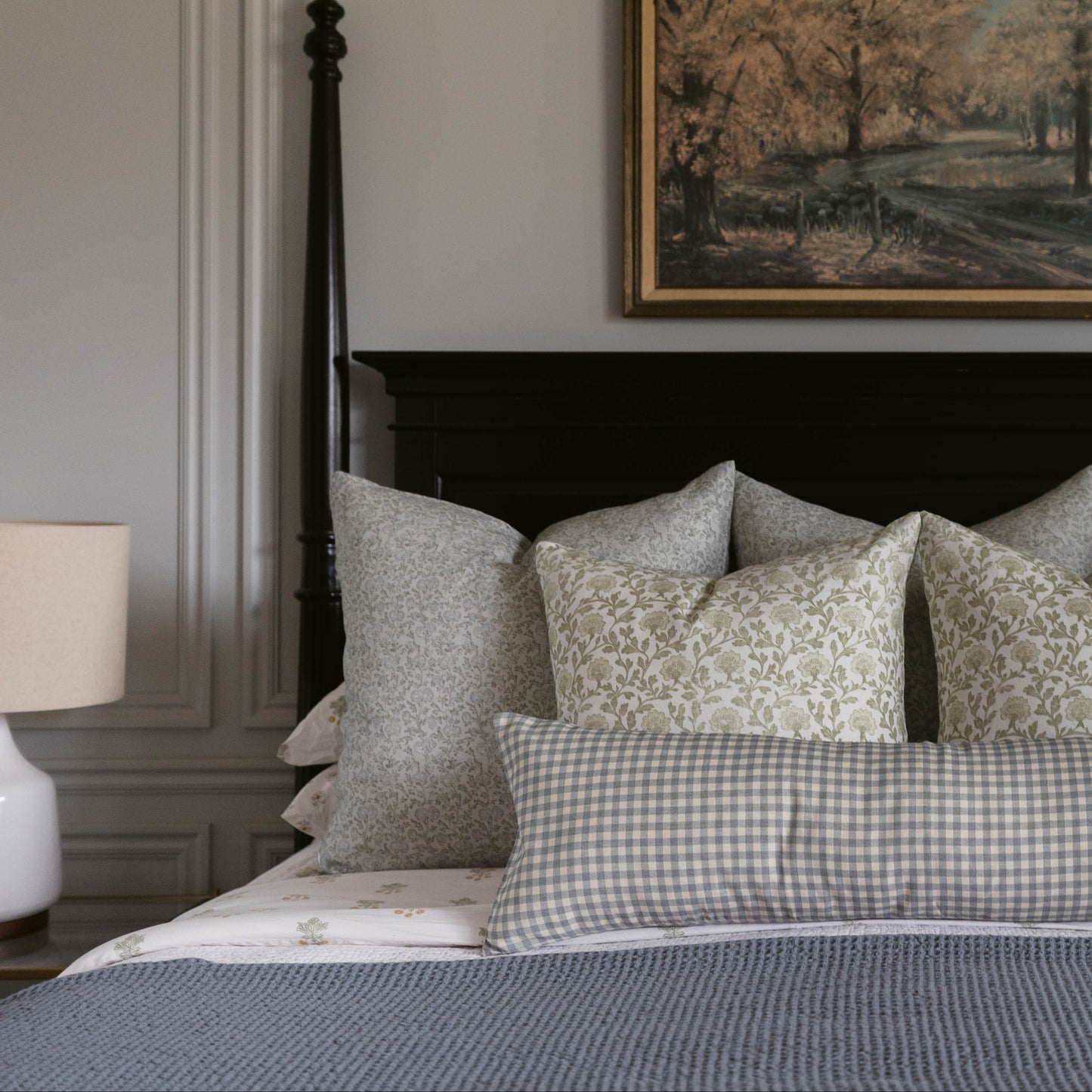Bed with layered linen pillows in neutral tones featuring solid, plaid, and floral patterns.